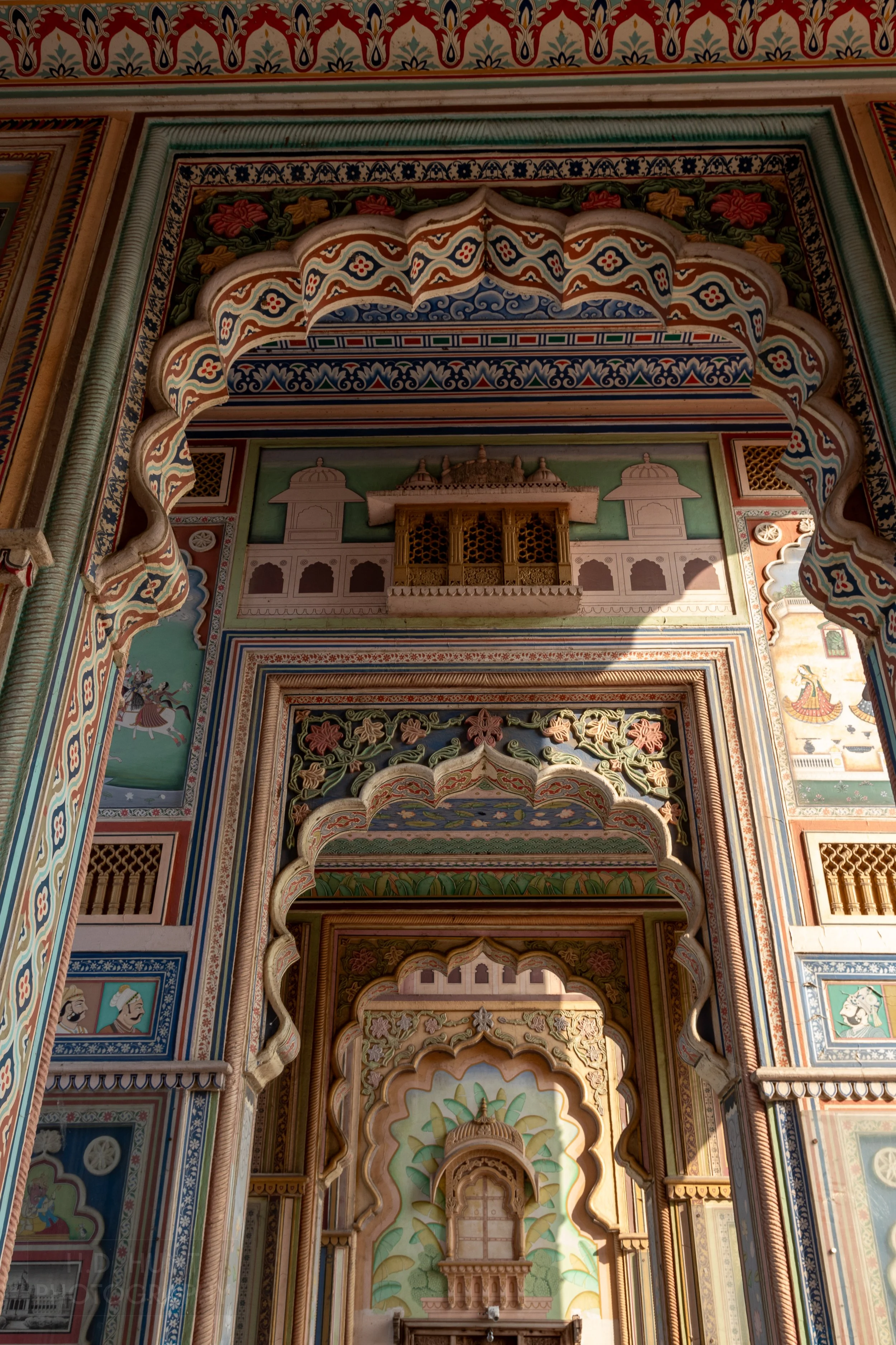 Multi-colored painted walls are seen through multiple archways at the Patrika Gate, Jaipur, India.