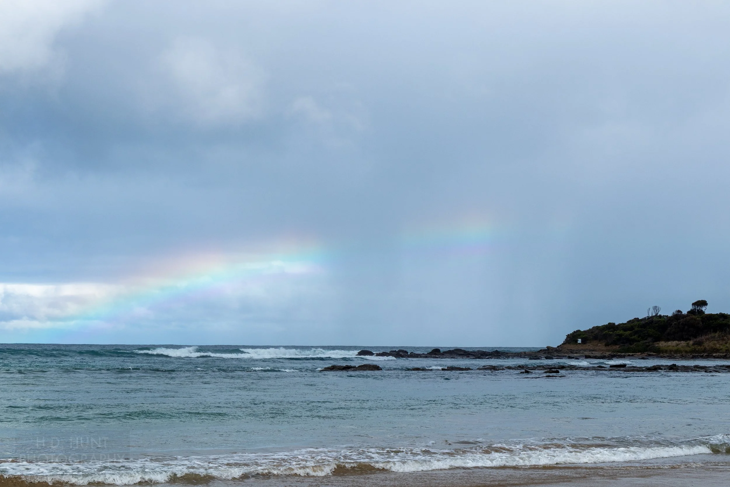 A rainbow is seen over the Southern Ocean along The Great Ocean Walk, Victoria, Australia.