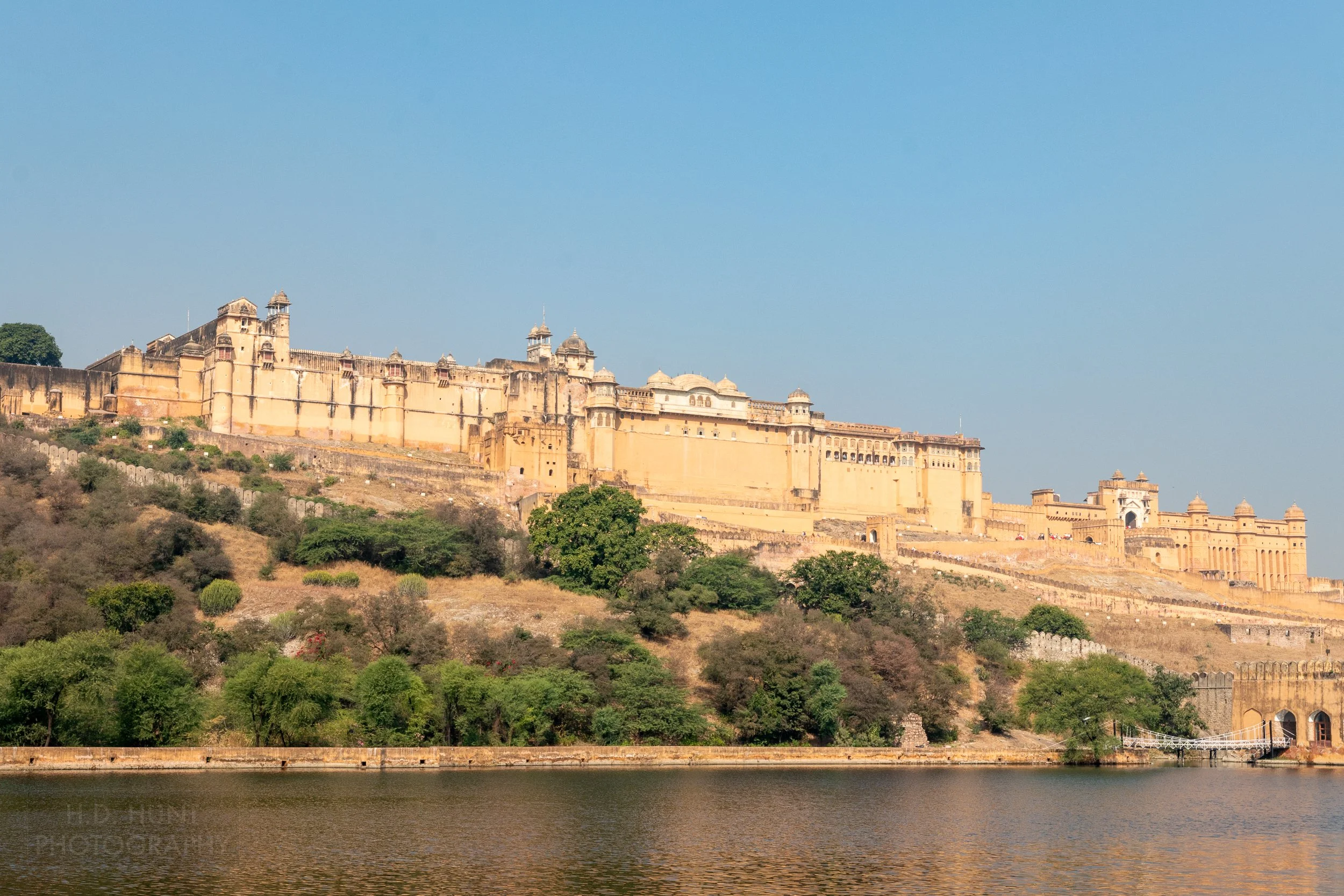 The yellow exterior walls of the massive Amber Fort are seen above a pond in Amer, India.