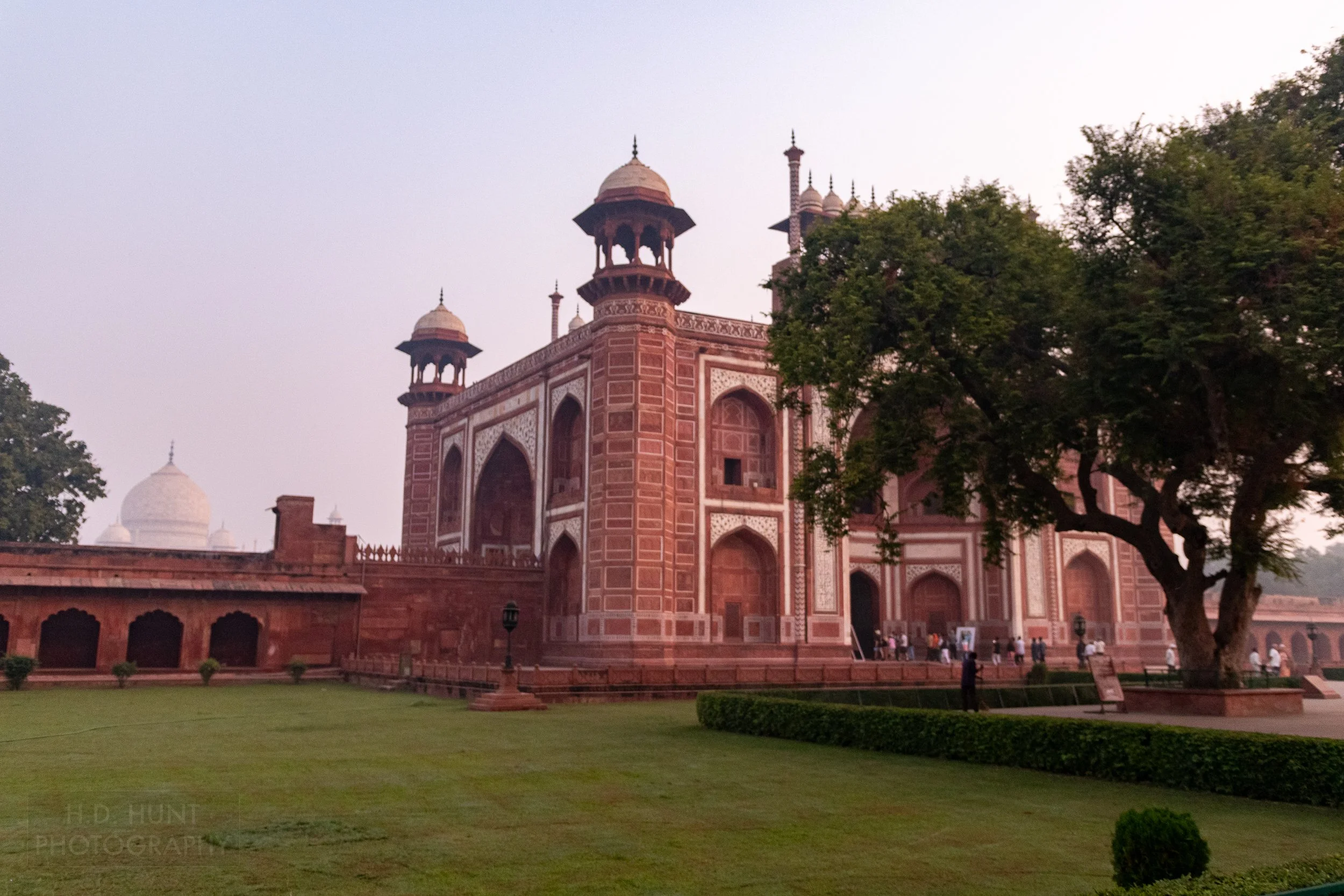 The deep red sandstone Main Gateway to the Taj Mahal is seen adjacent to manicured grass, Agra, India.