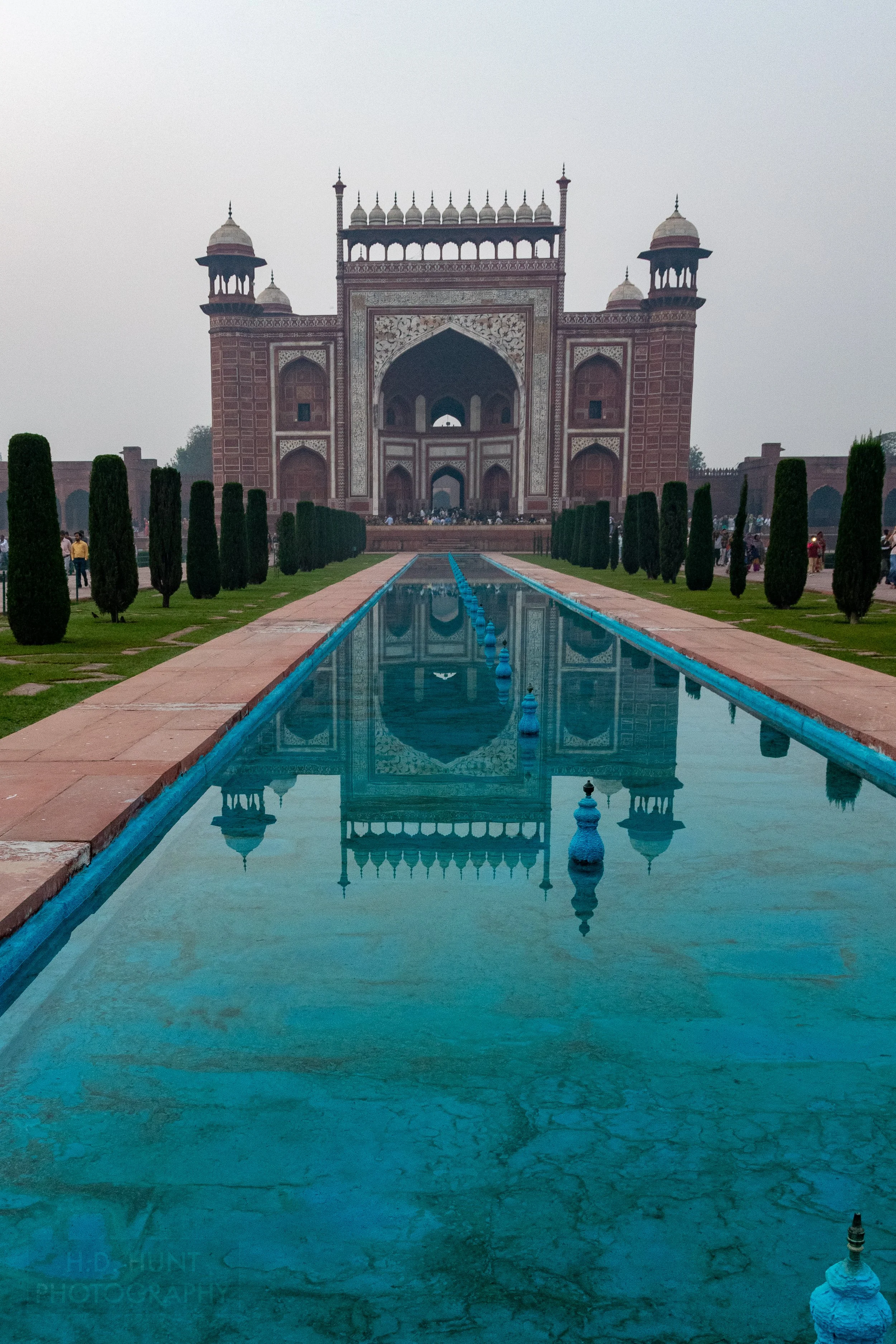 The red sandstone Main Gate of Taj Mahal is reflected in a blue pool, Agra, India.