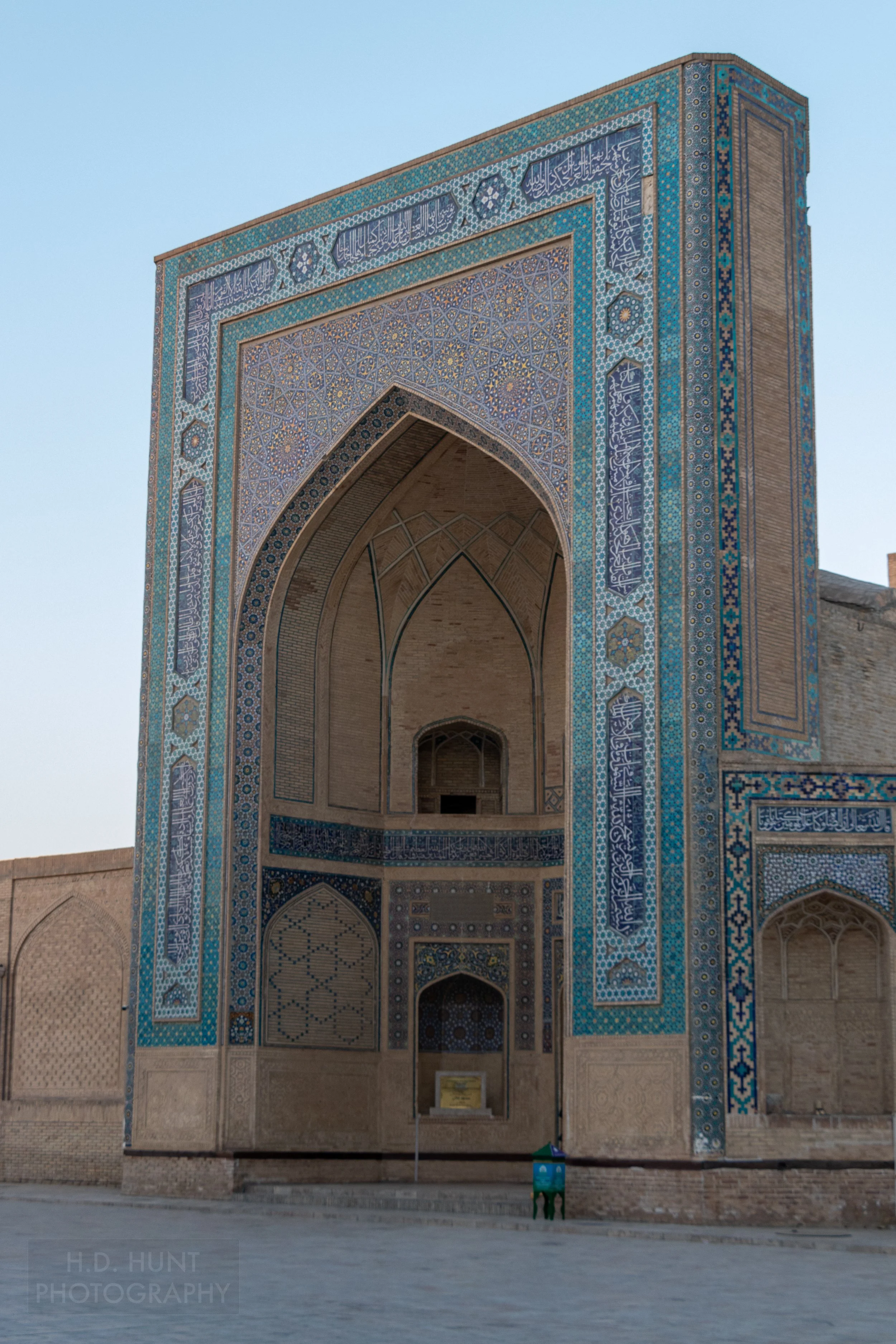 The light and dark blue tiled iwan of Kalan Mosque is illuminated by the sunrise, Bukhara, Uzbekistan.