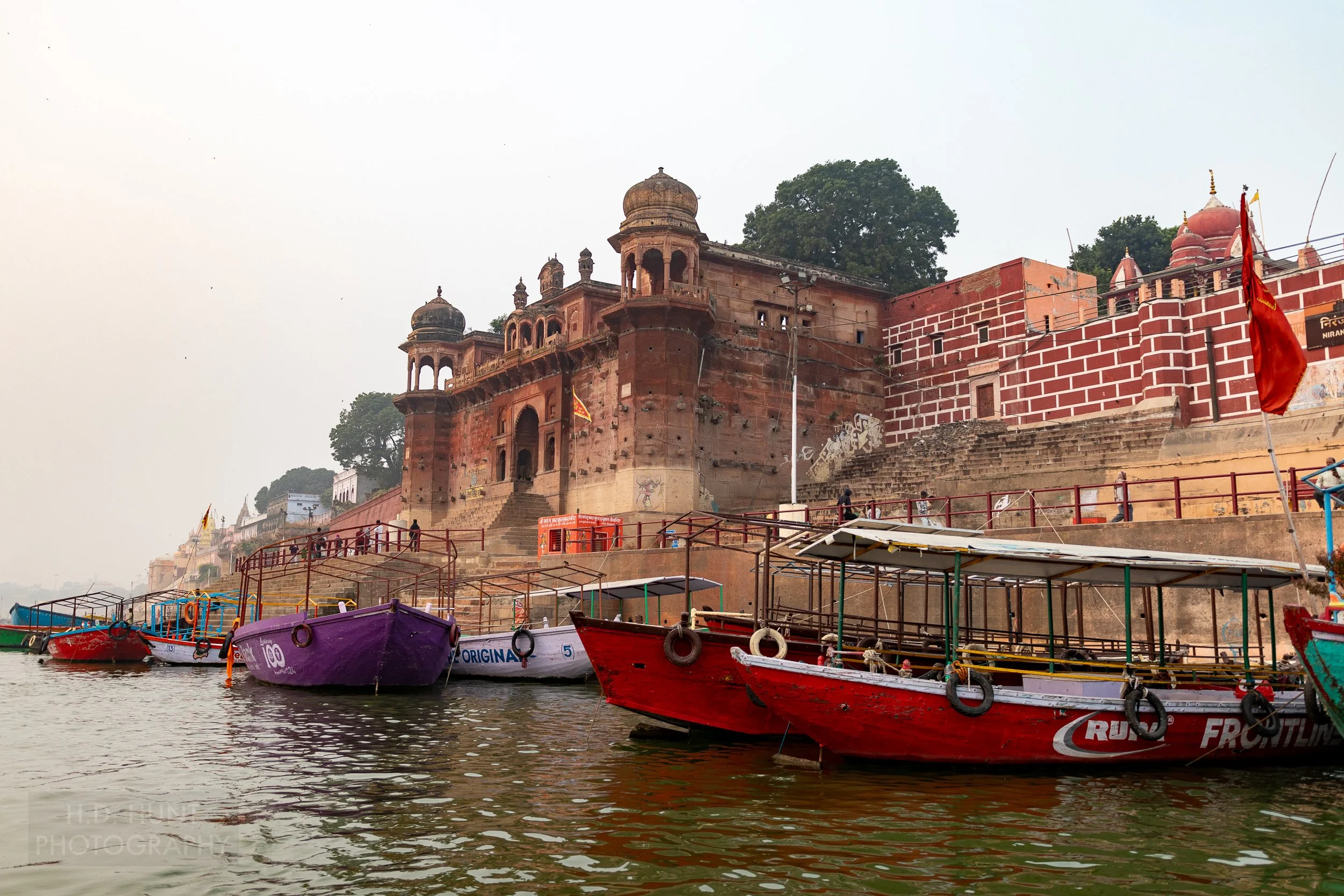 Several boats in the Ganges River are tied up in front of a temple, Varanasi, India.