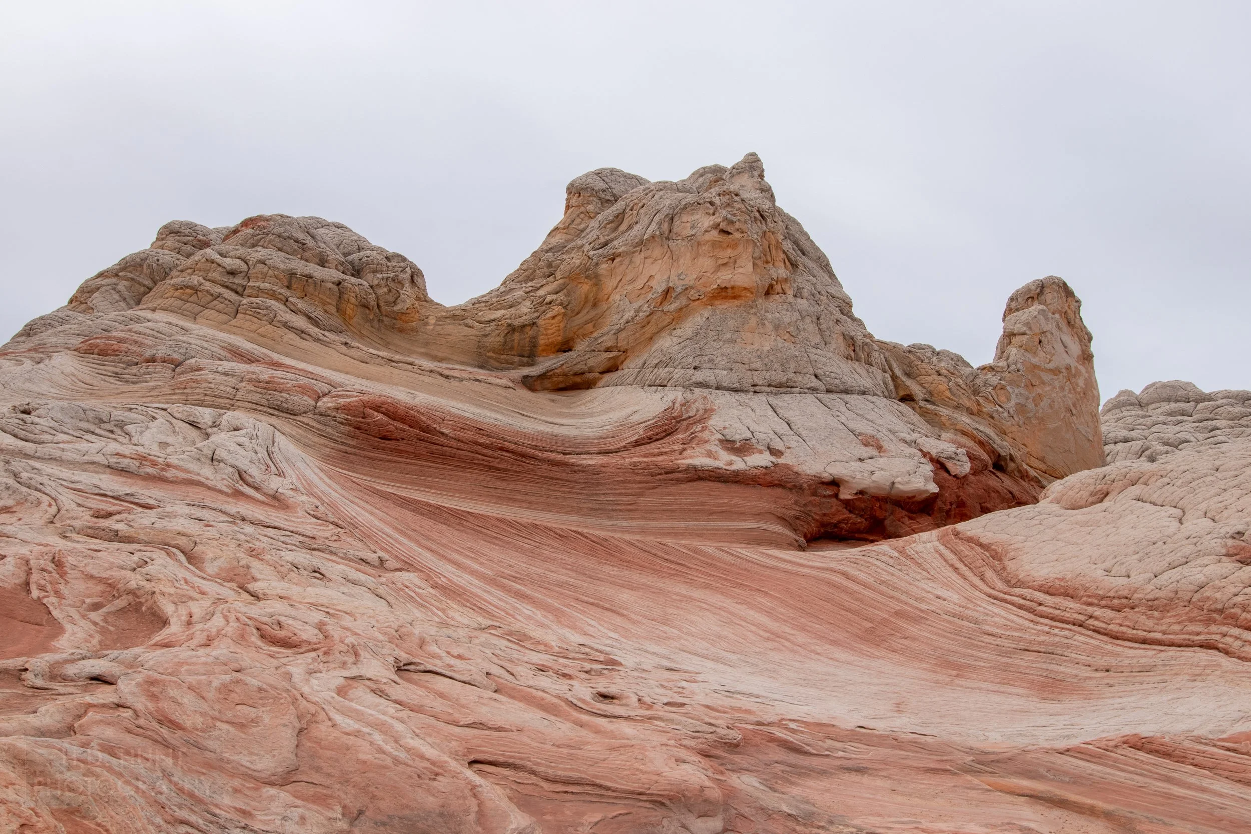 Striped and folded red and white sandstone is topped with a hill of white rock, White Pocket, Vermillion Cliffs National Monument, Arizona, United States.