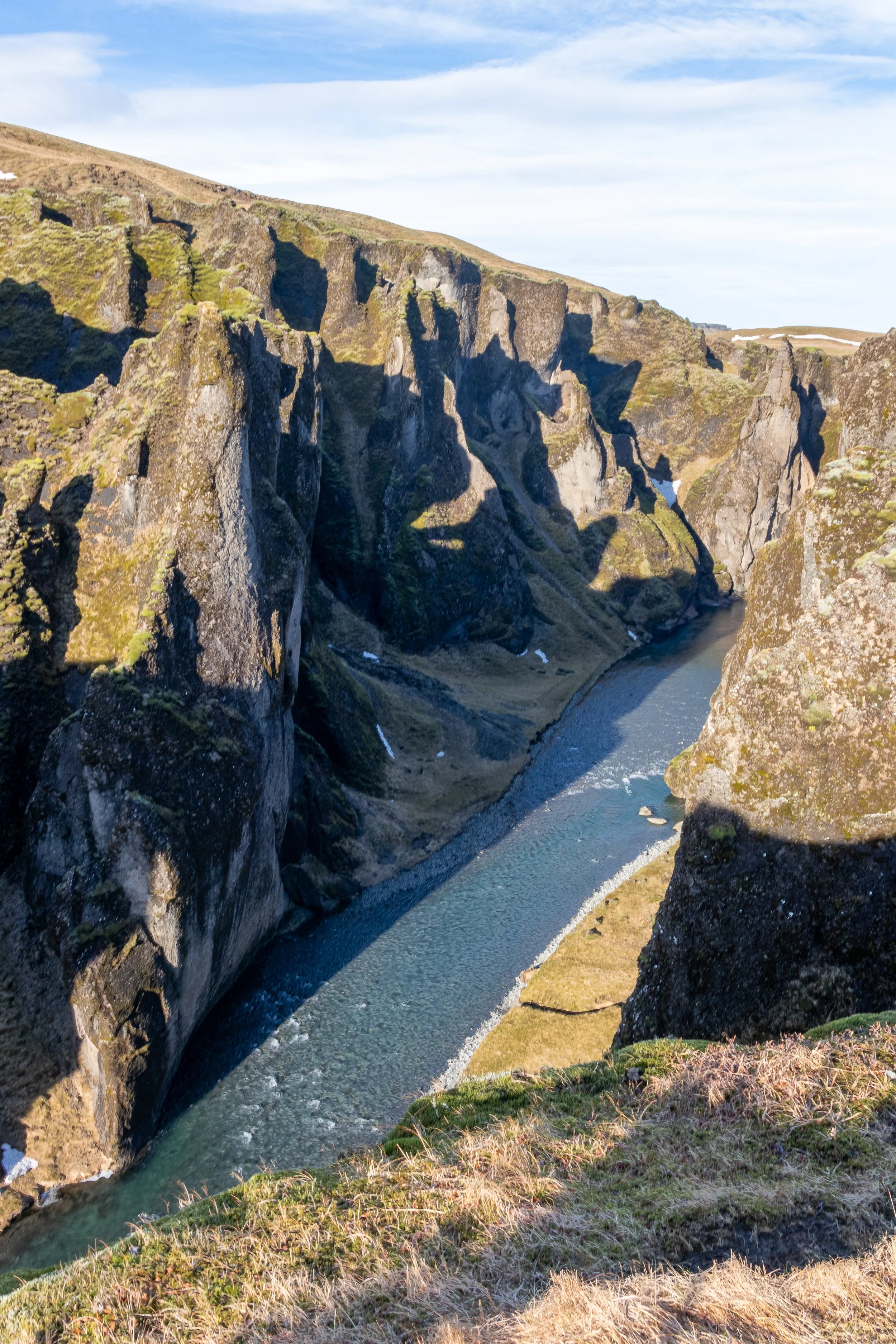 A river runs between very tall stone walls in a deep canyon, Fjaðrárgljúfur, Iceland.