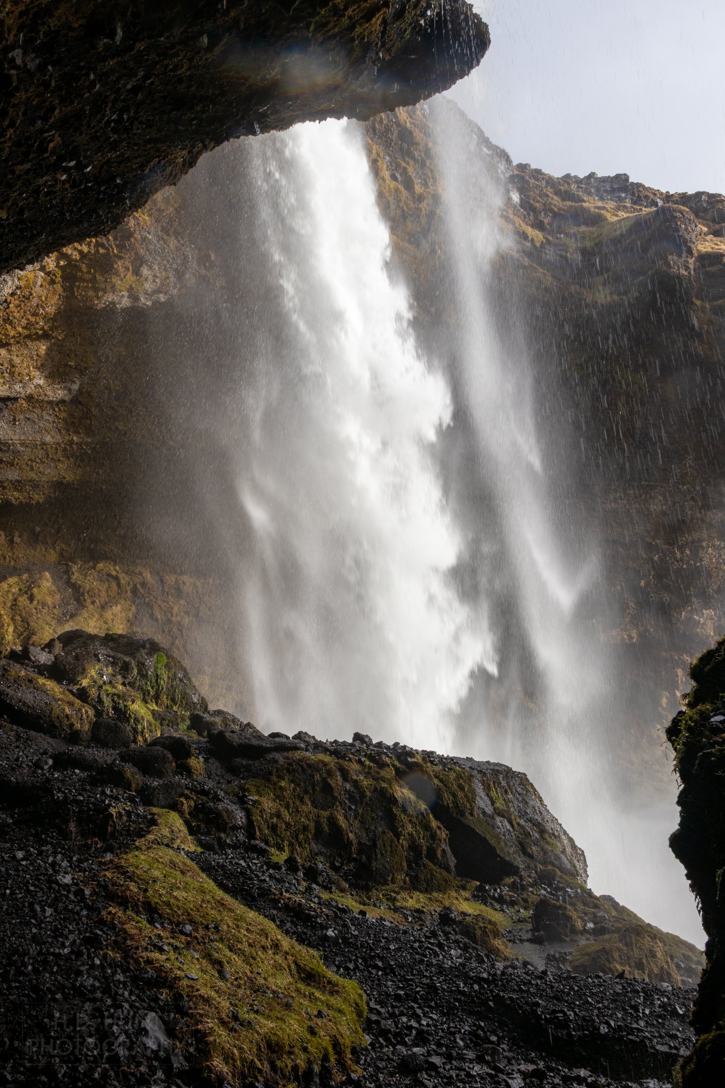 Water pours over the edge of a dark rock face at Kvernufoss, Iceland.