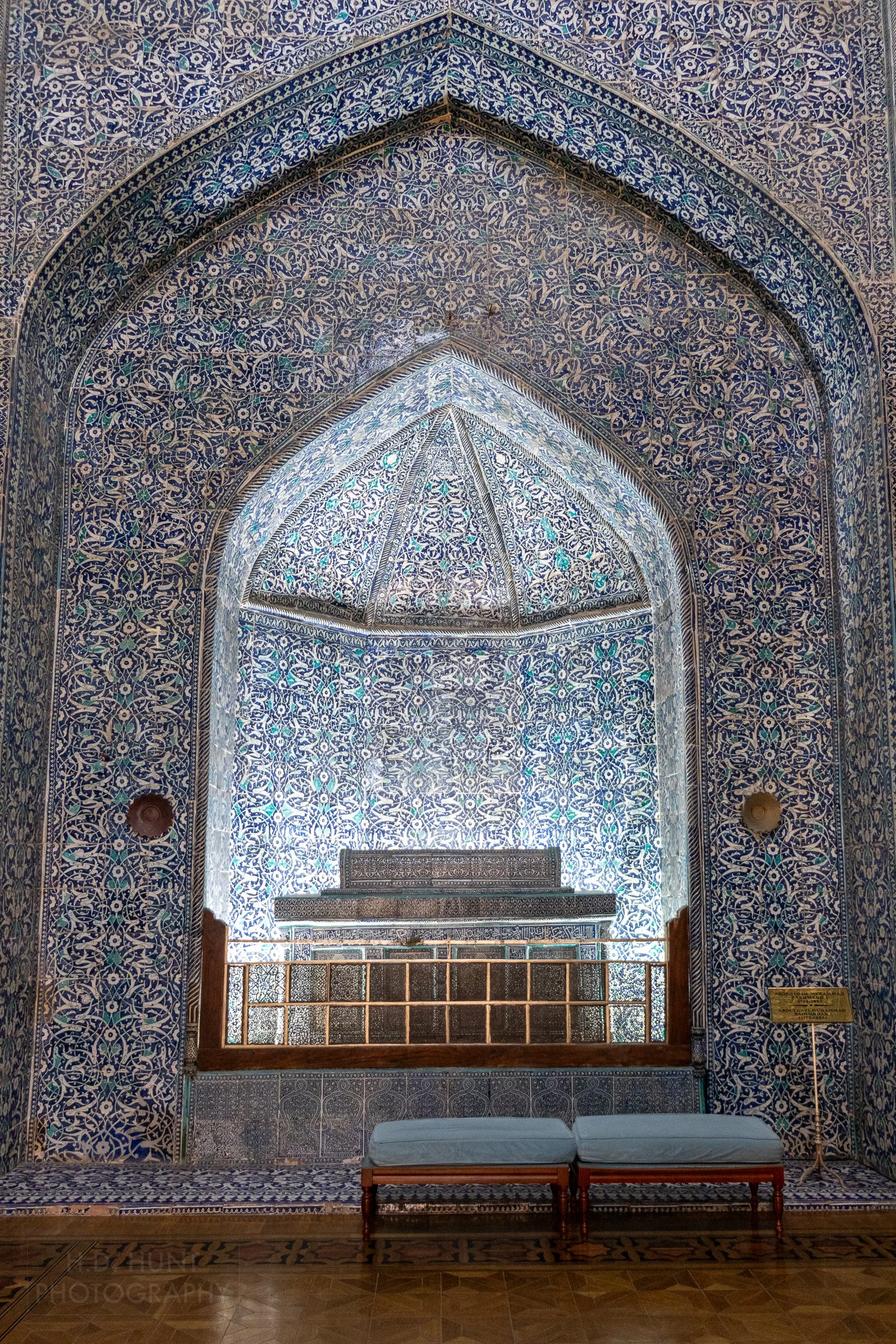 A sarcophagus adorned with tiles sits in an ornate alcove within the Pahlavan Mahmoud Mausoleum, Khiva, Uzbekistan.