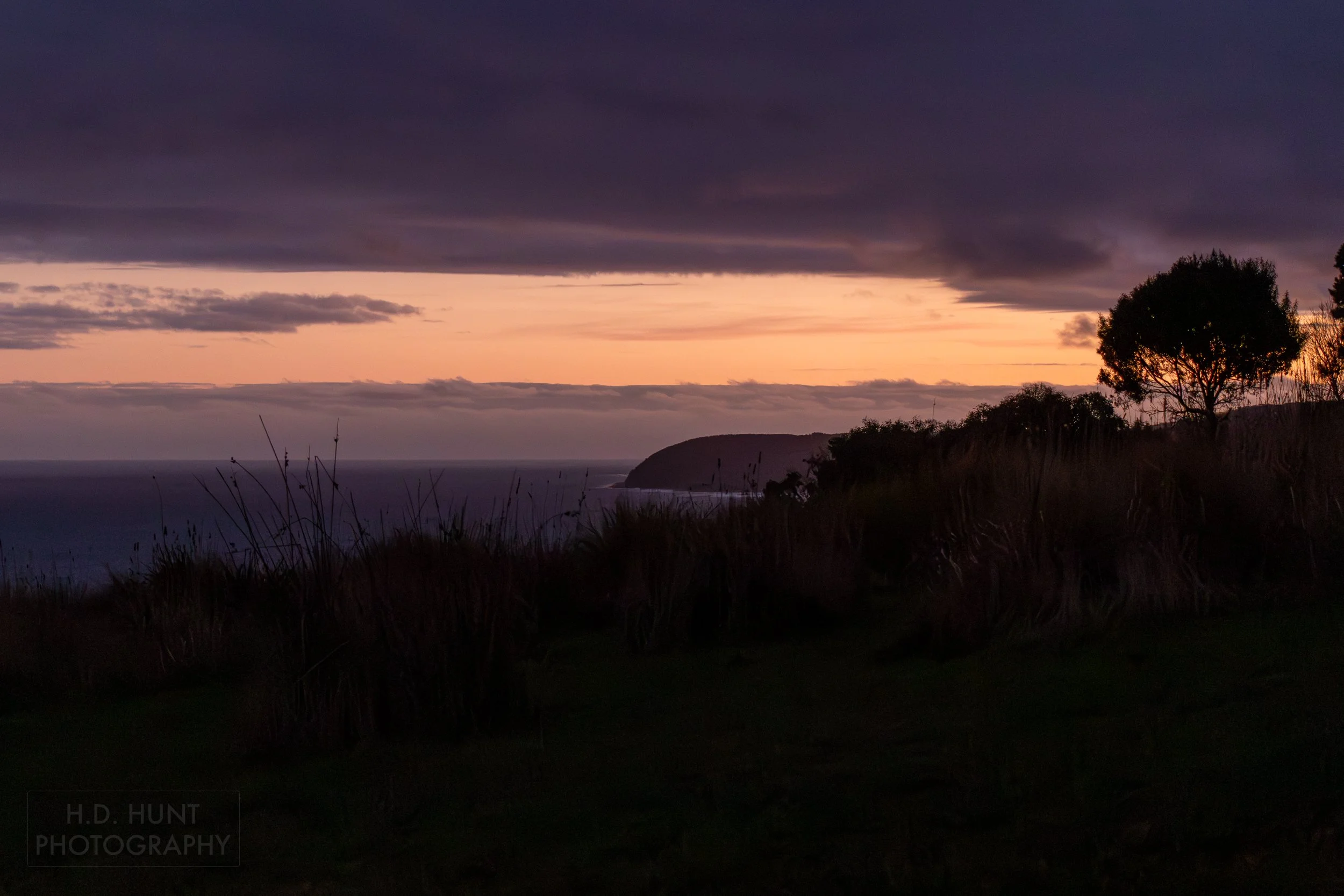 The sun sets behind cliffs along the Southern Ocean at Wildlife Wonders, Apollo Bay, Victoria, Australia.