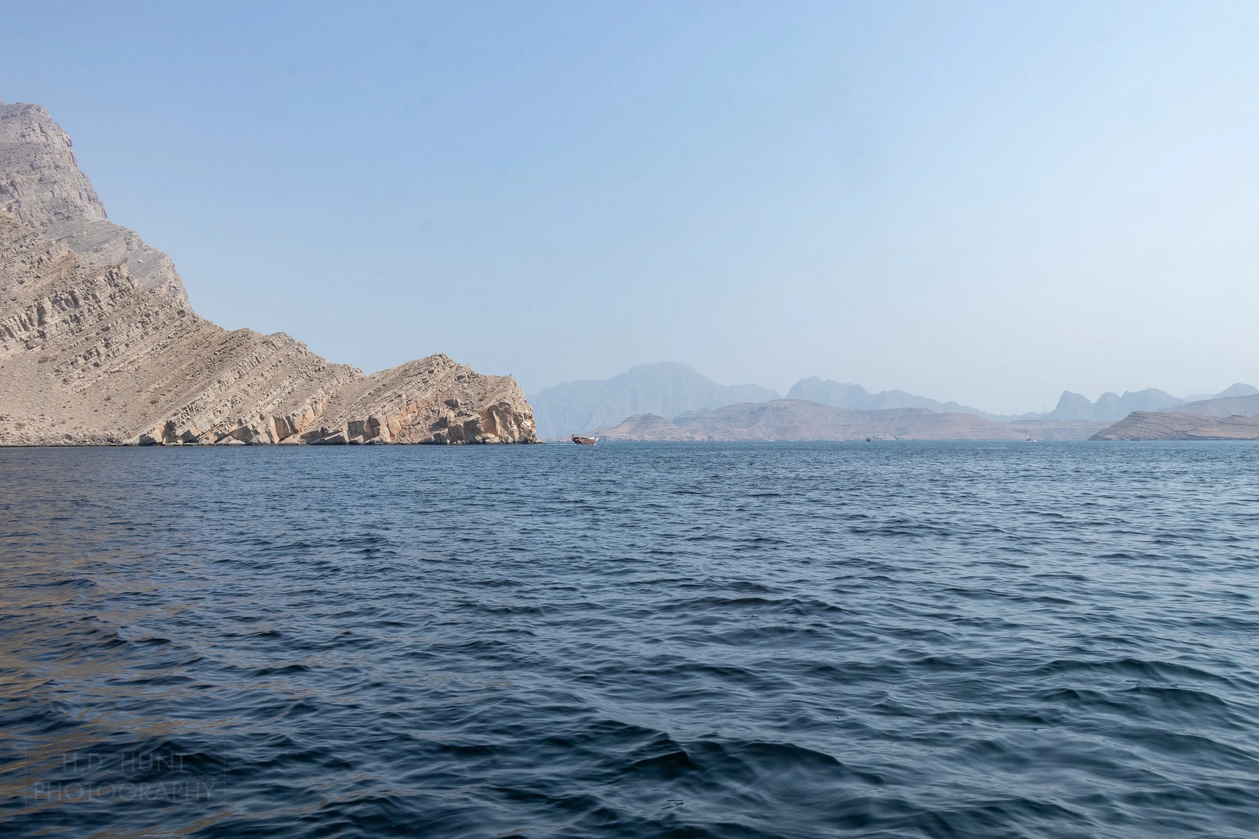 Jagged and angular cliffs meet the sea in the Musandam Peninsula, Oman.