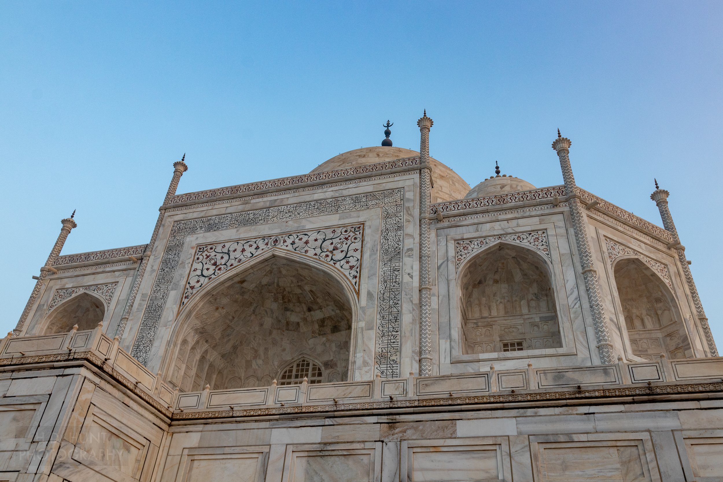 A close-up of the black marble calligraphy against the white marble mausoleum building of Taj Mahal, Agra, India.