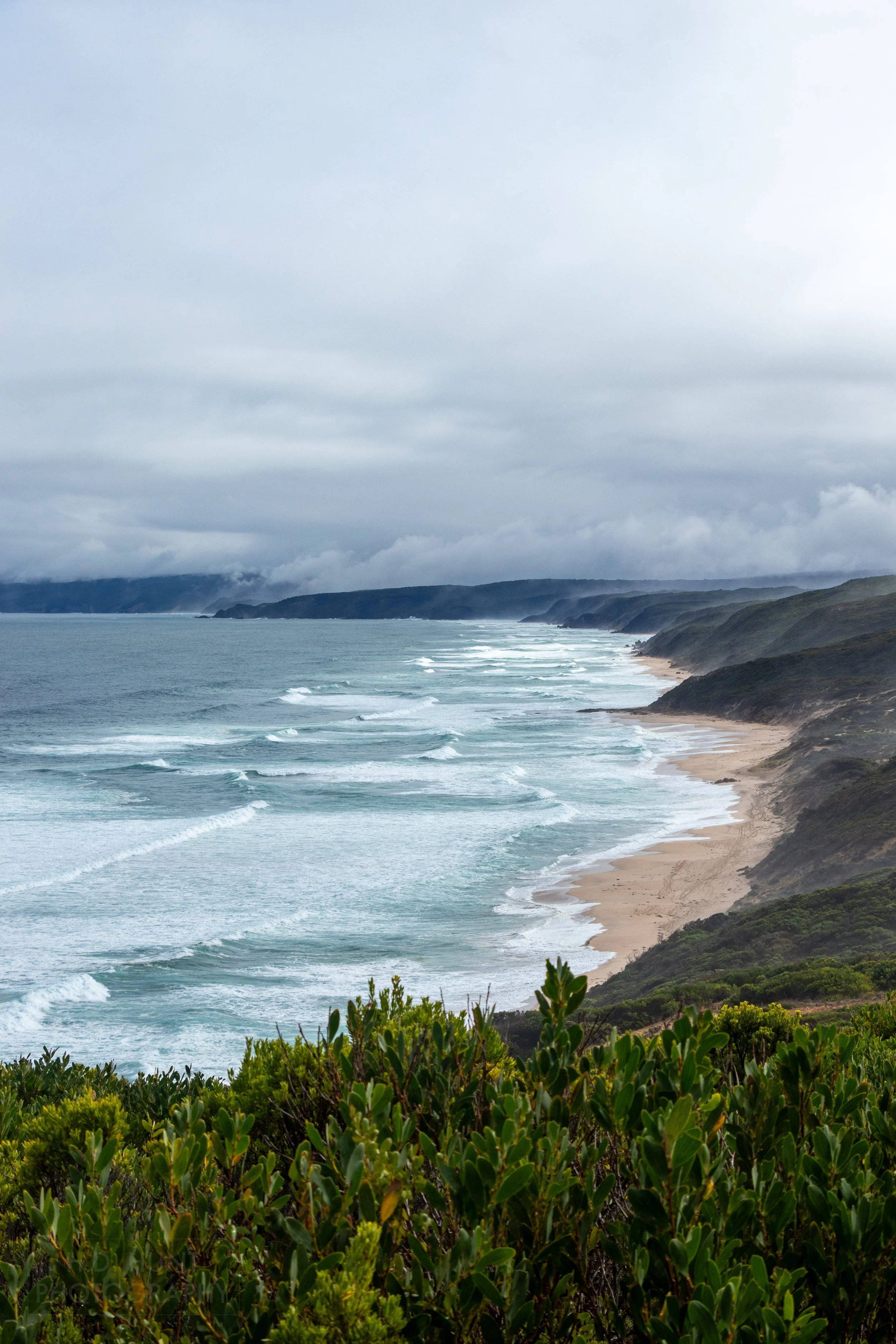 Waves lash against the beach beneath low cliffs along the Southern Ocean adjacent to The Great Ocean Walk, Victoria, Australia.