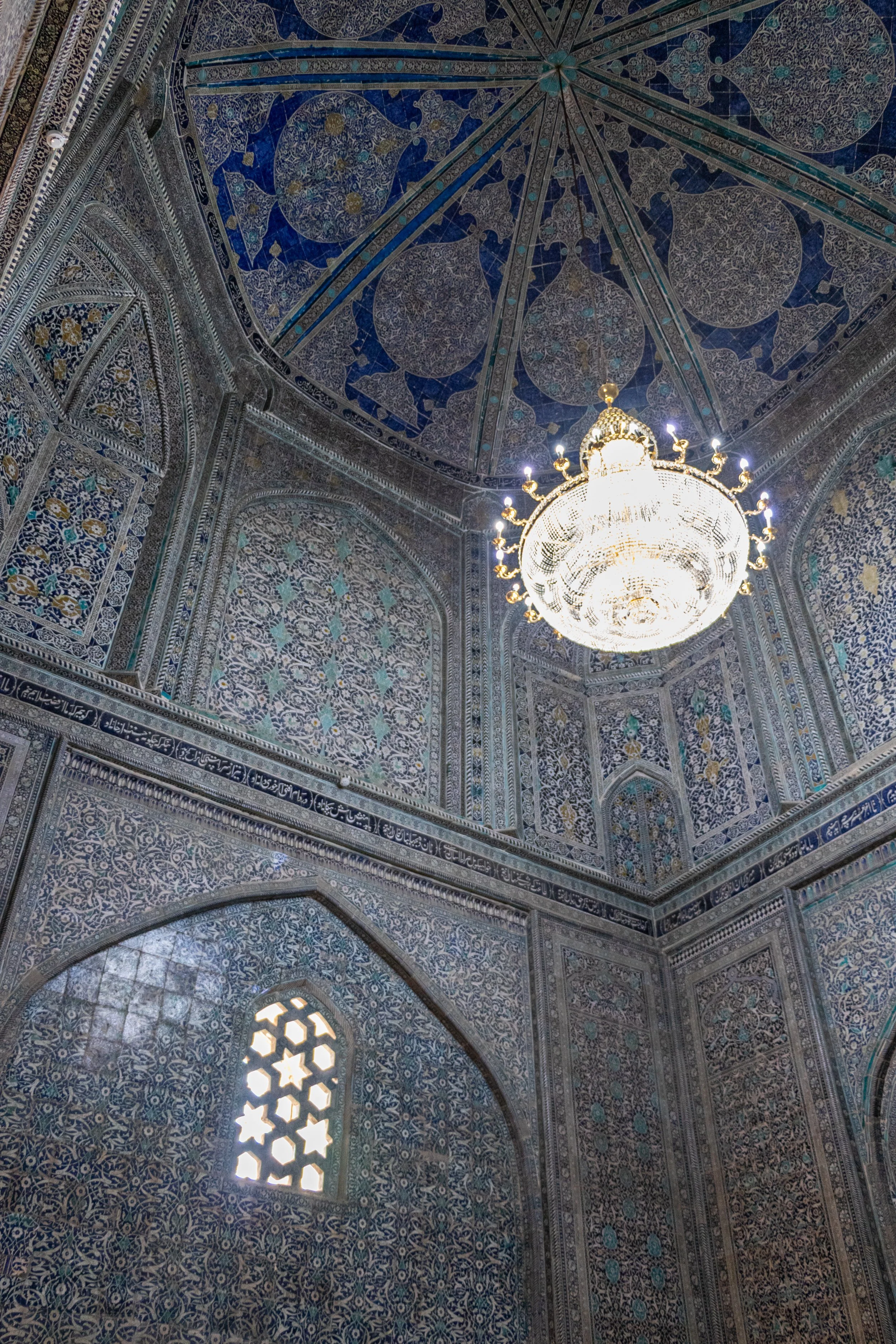 A chandelier illuminates an elegantly-tiled room within the Pahlavan Mahmoud Mausoleum in Khiva, Uzbekistan.