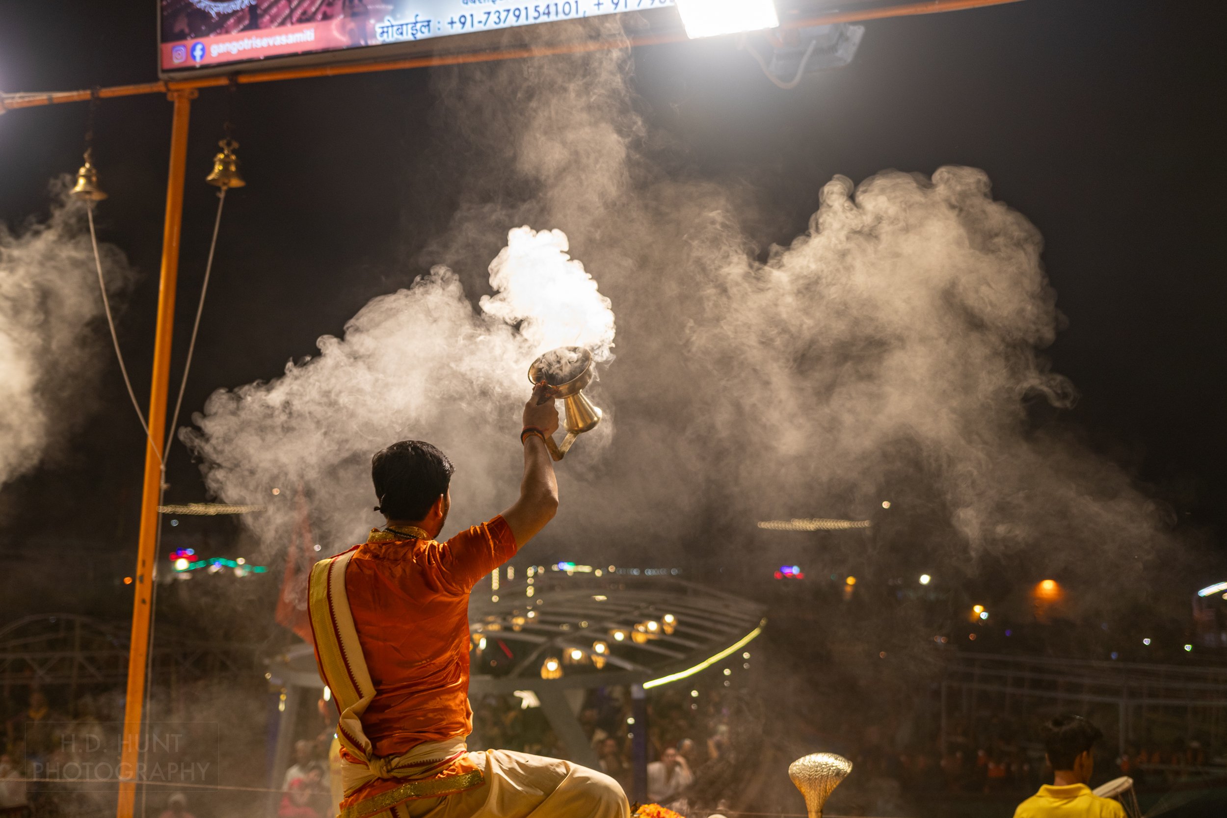 A man wearing a religious outfit creates smoke during a Hindu religious ceremony called arti, Varanasi, India.