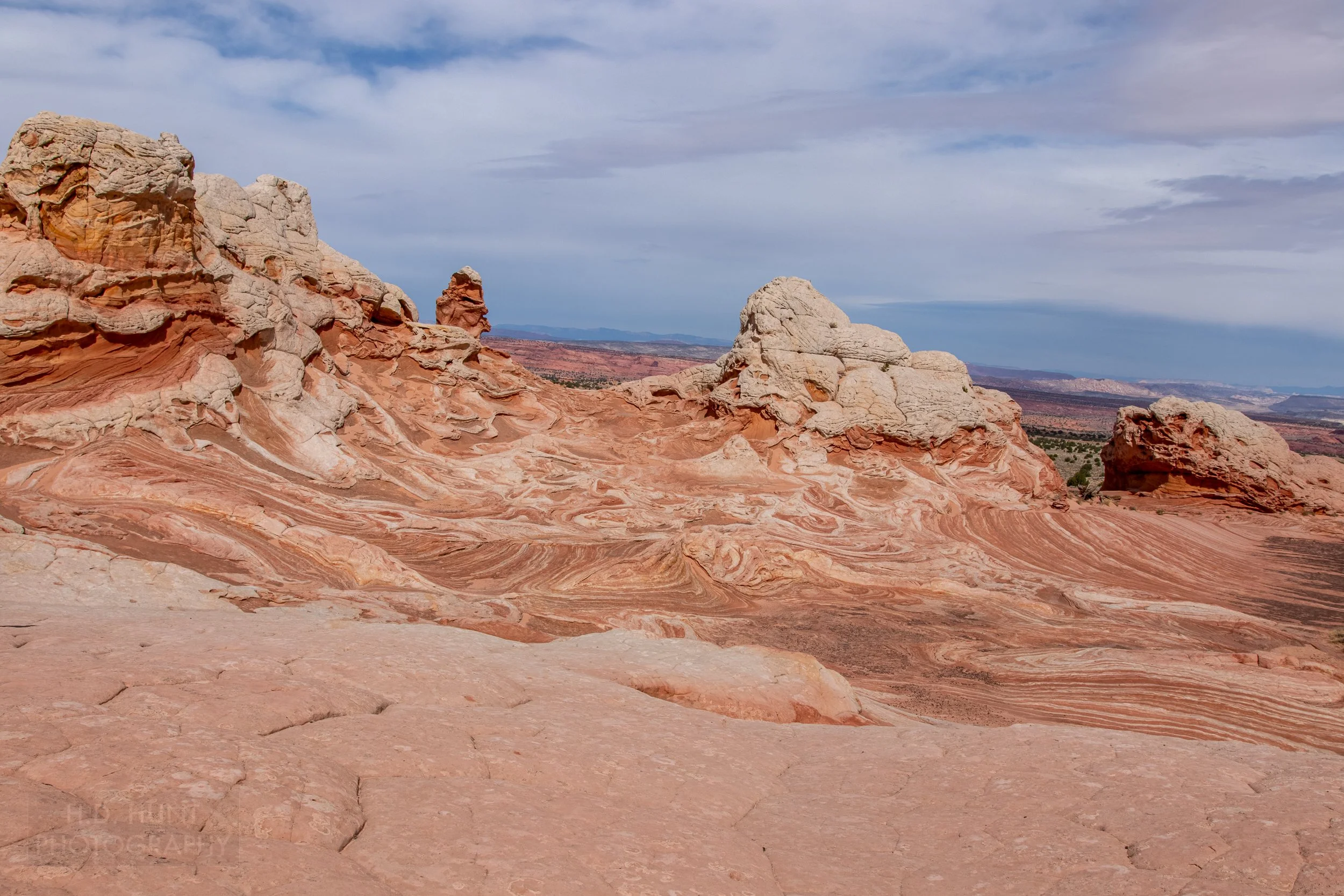 A heavily deformed swirling red and white sandstone bedrock sits beneath mounds of white rock in White Pocket, Vermillion Cliffs National Monument, Arizona, United States.
