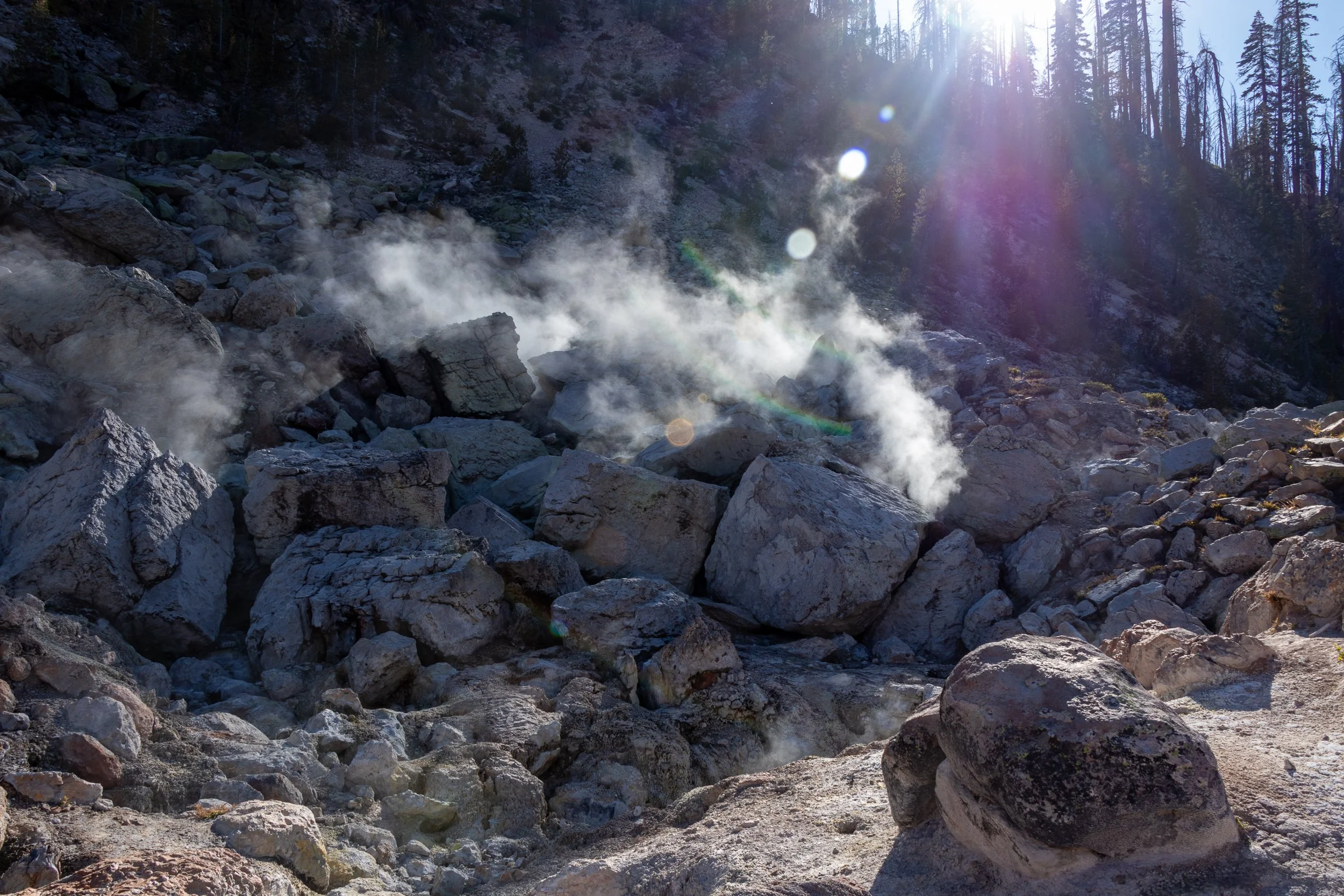 Steam rises from a pile of large grey boulders, Devils Kitchen, Lassen Volcanic National Park, California, United States.