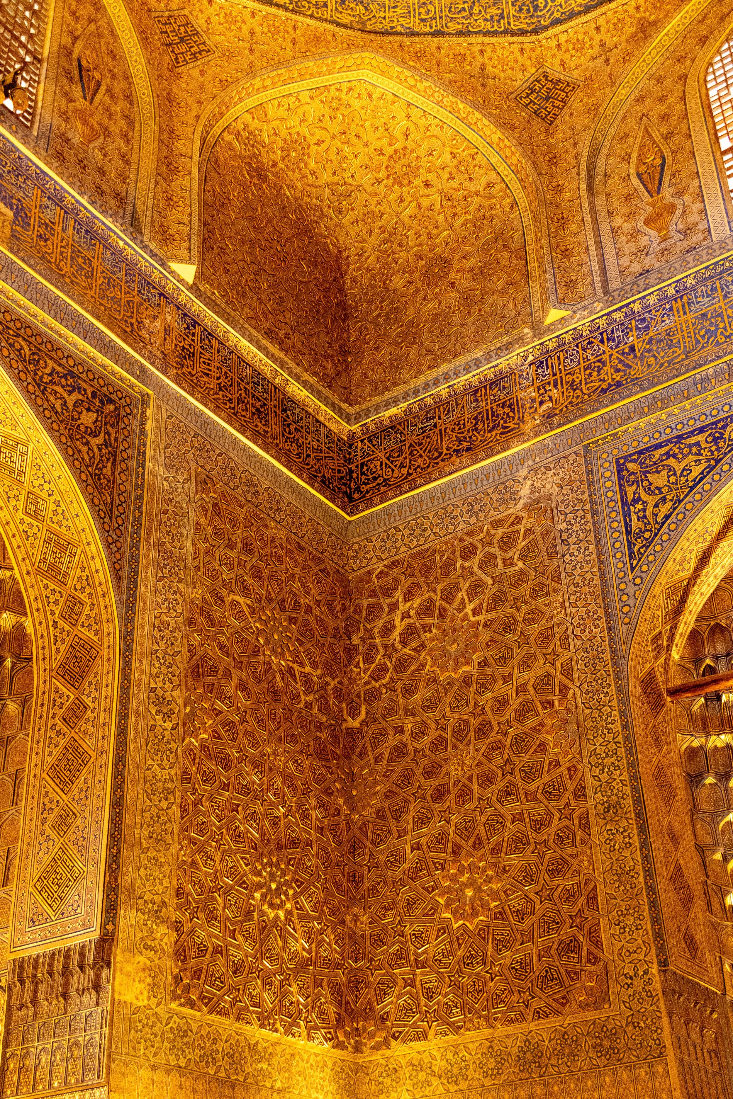 Gold-colored patterned wall inside Guri Amir mausoleum in Samarkand, Uzbekistan.