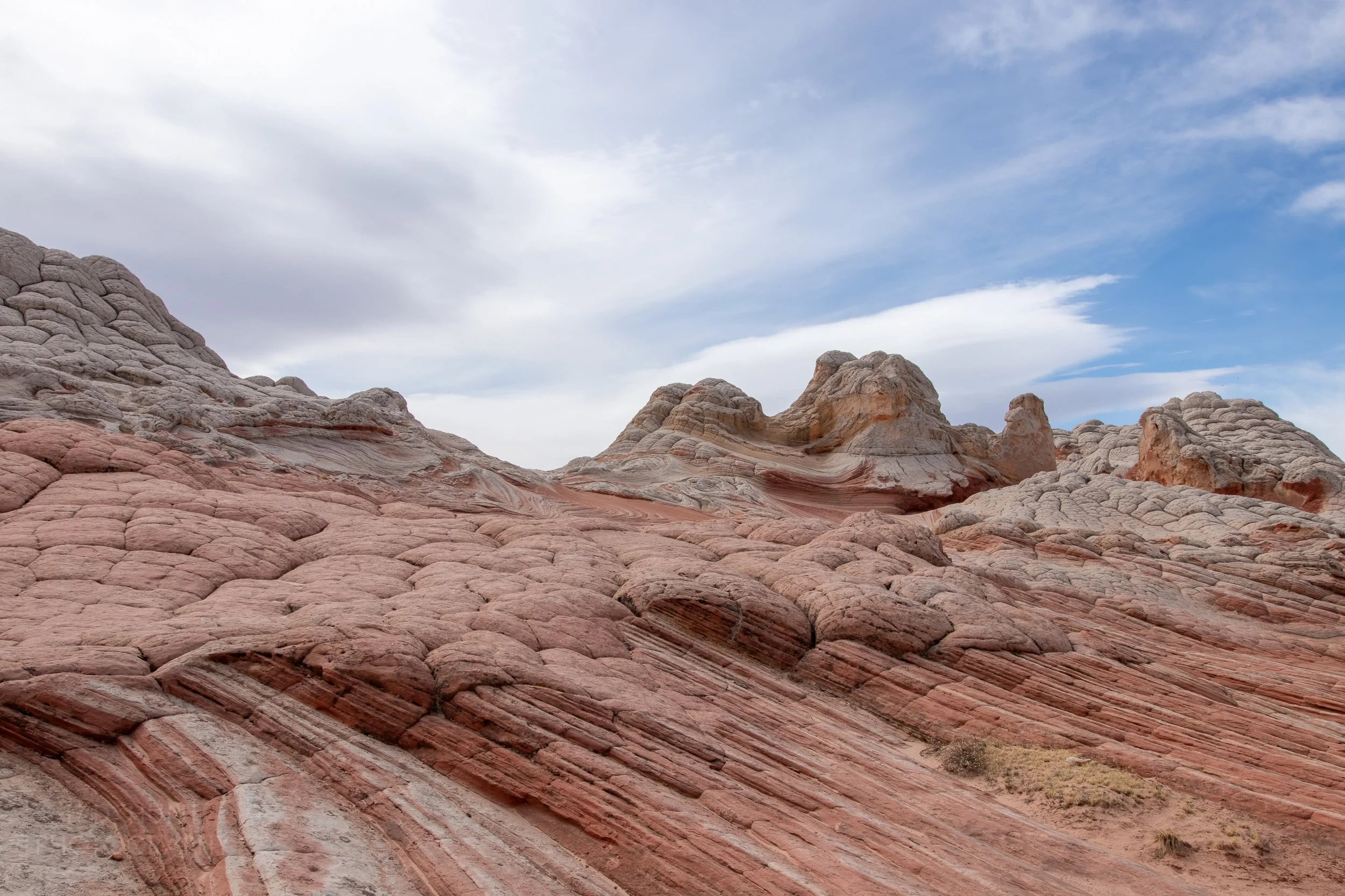 Heavily deformed and folded red and white sandstone is covered by mounds of white rock, White Pocket, Vermillion Cliffs National Monument, Arizona, United States.