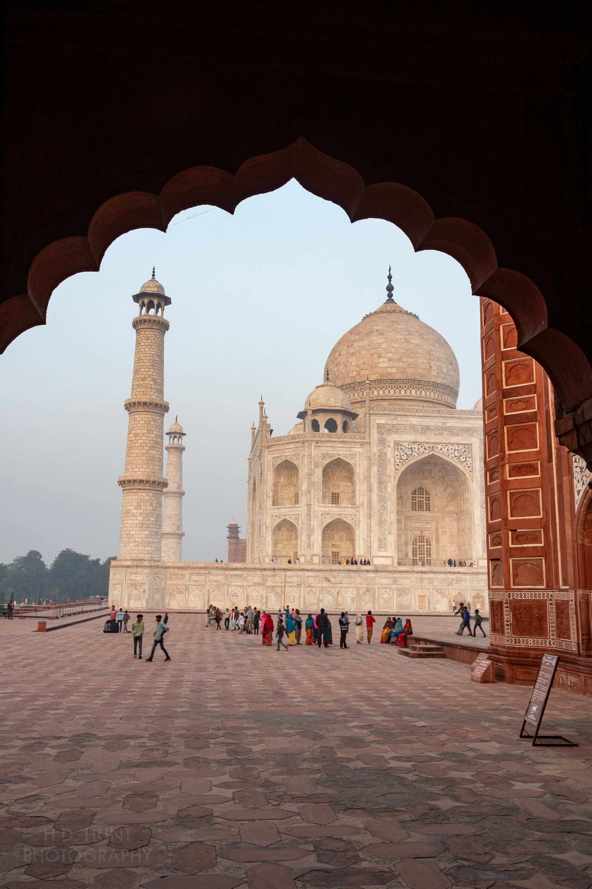 The main dome and two minarets of the white marble Taj Mahal are seen through an archway with circular edging, Agra, India.