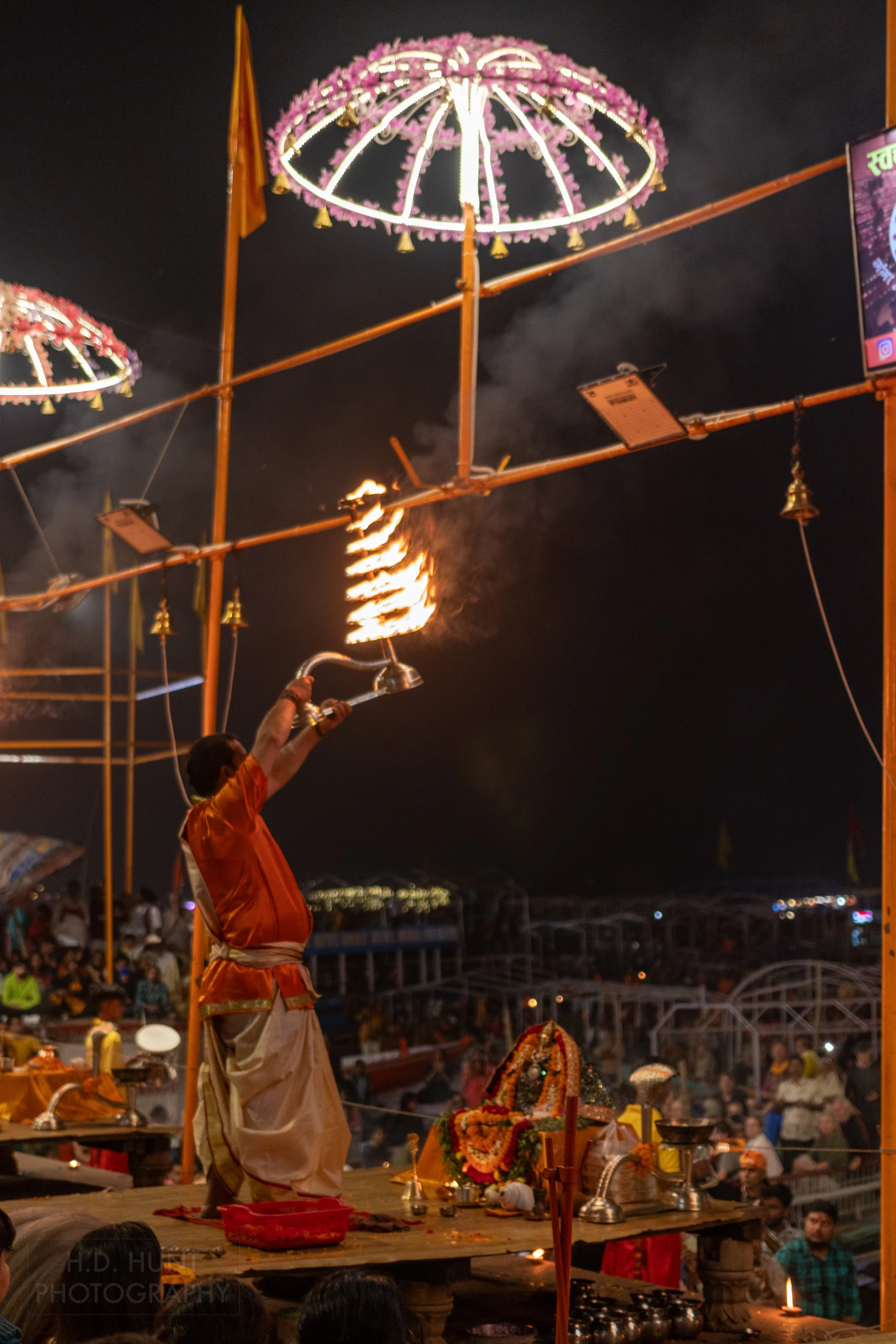 A man holds a large metal candle holders above his head during a Hindu religious ceremony called arti, Varanasi, India.