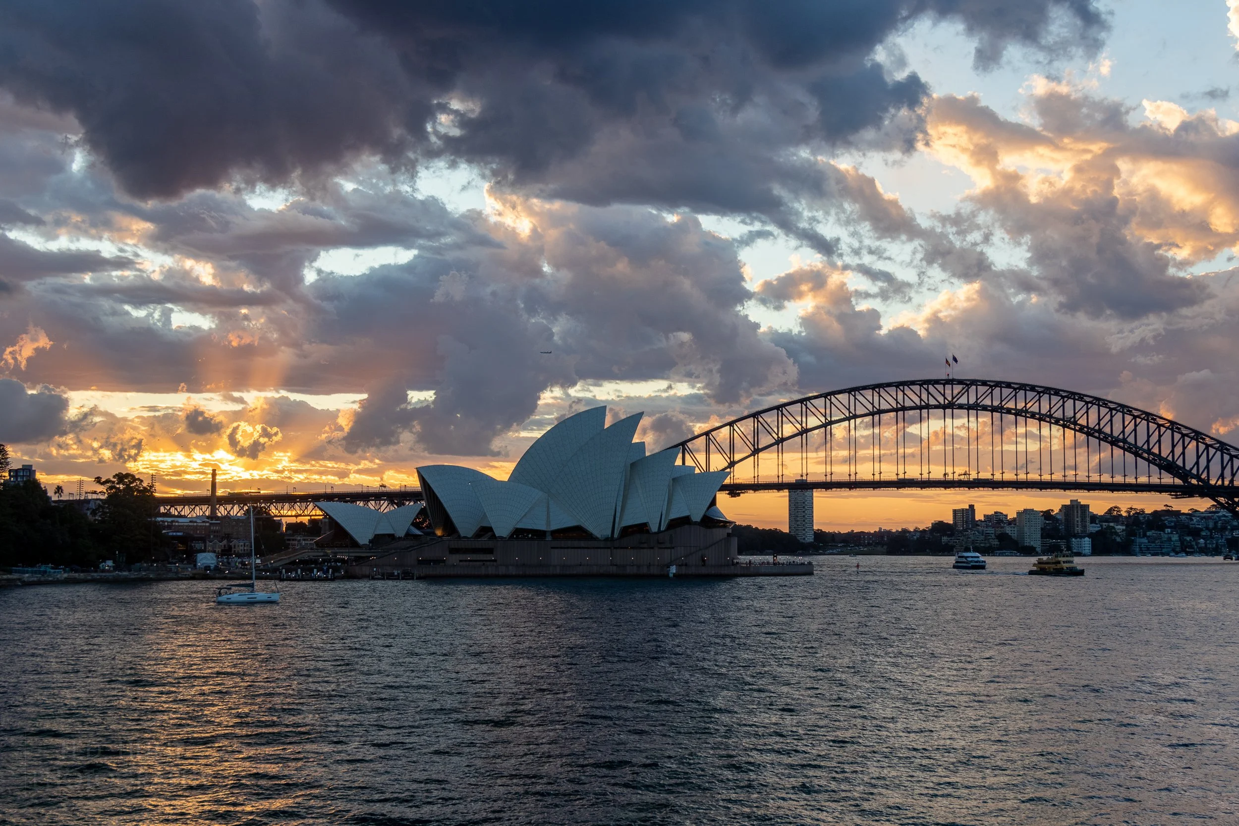 Sunlight peeks through clouds behind the Sydney Opera House, Sydney, Australia.