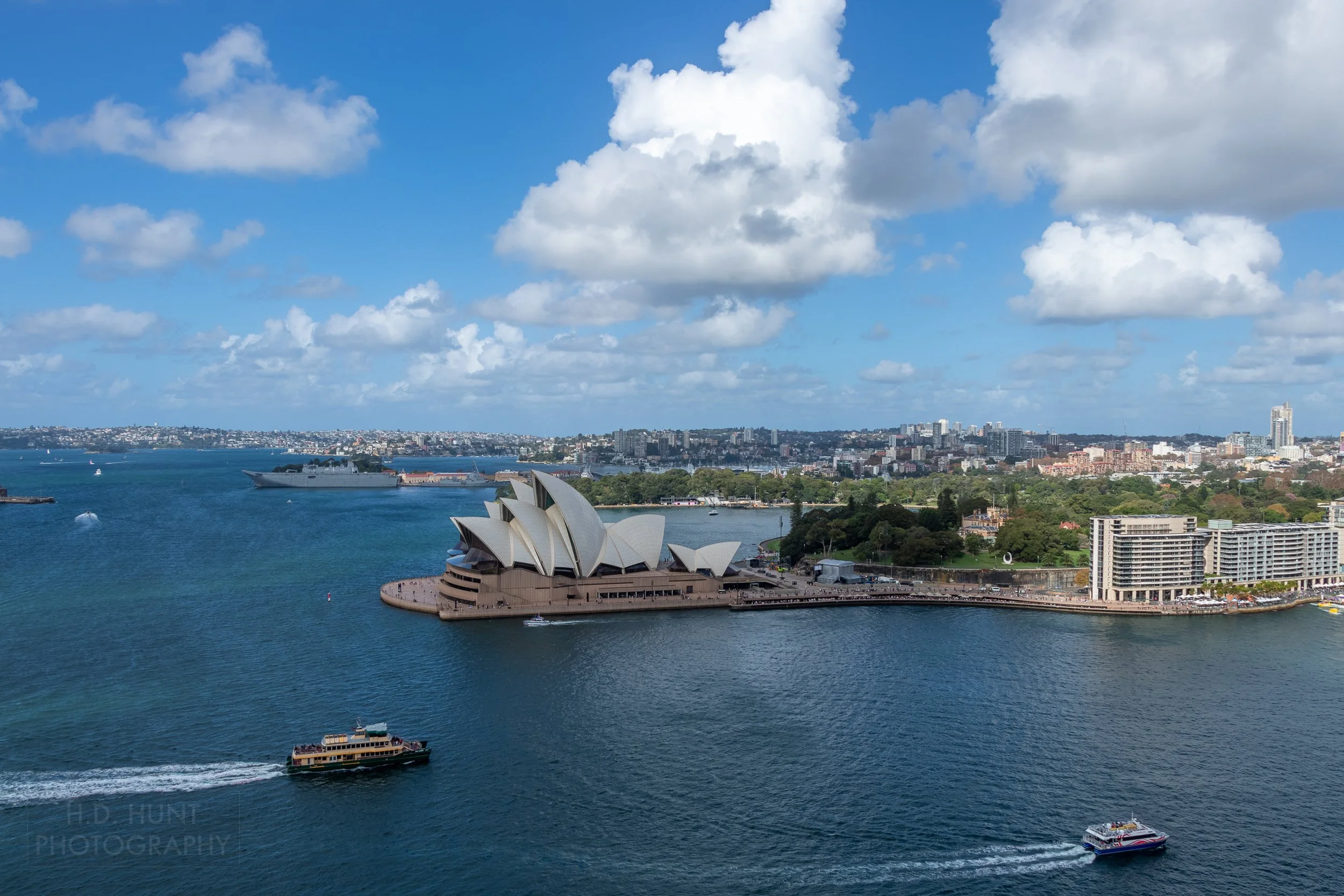 Ferry boats cross into Circular Quay in front of the Sydney Opera House beneath a cloudy sky, Sydney, Australia.