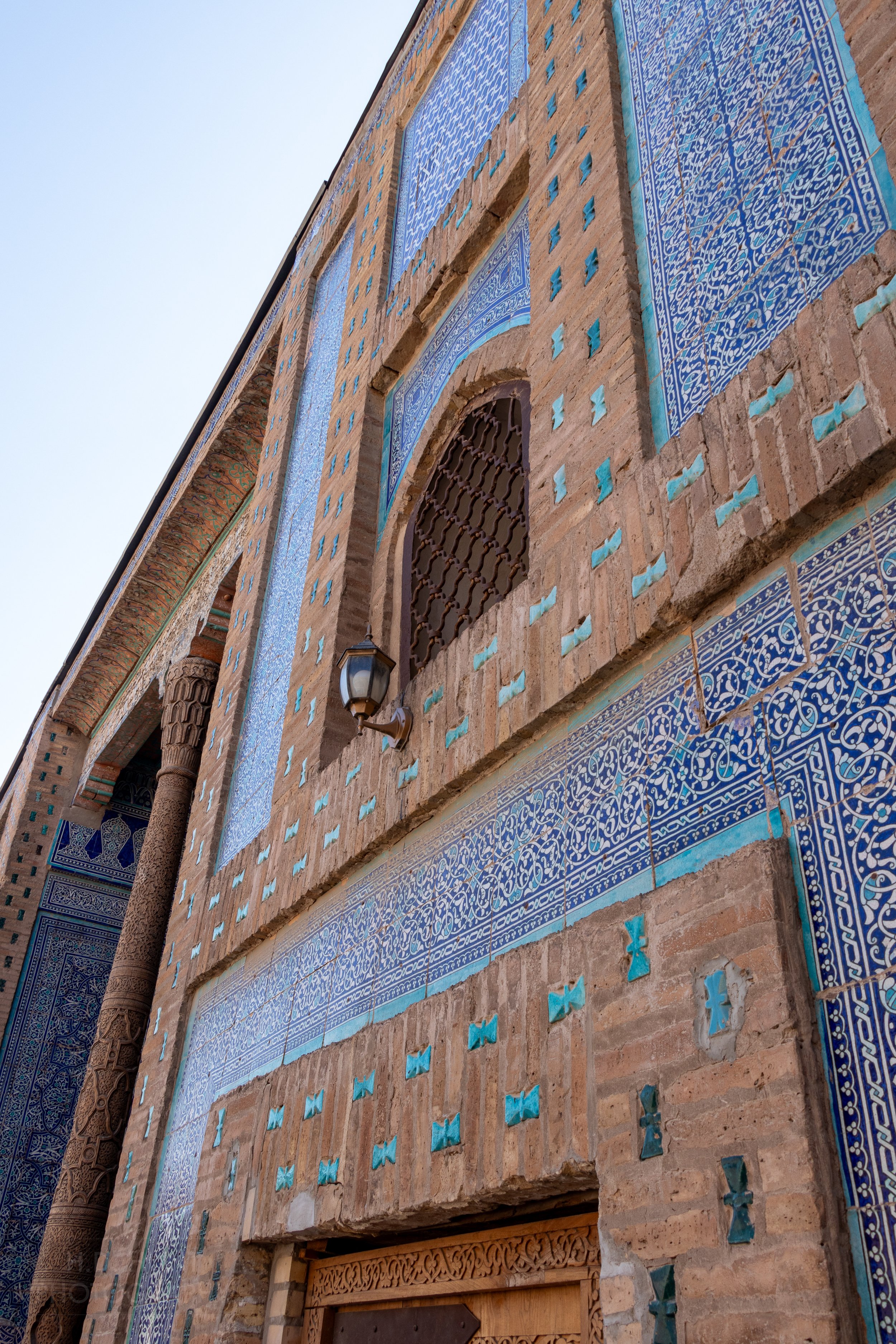Blue and white tile work surrounds a brown brick doorway in the harem at the Toshhovli Palace, Khiva, Uzbekistan.