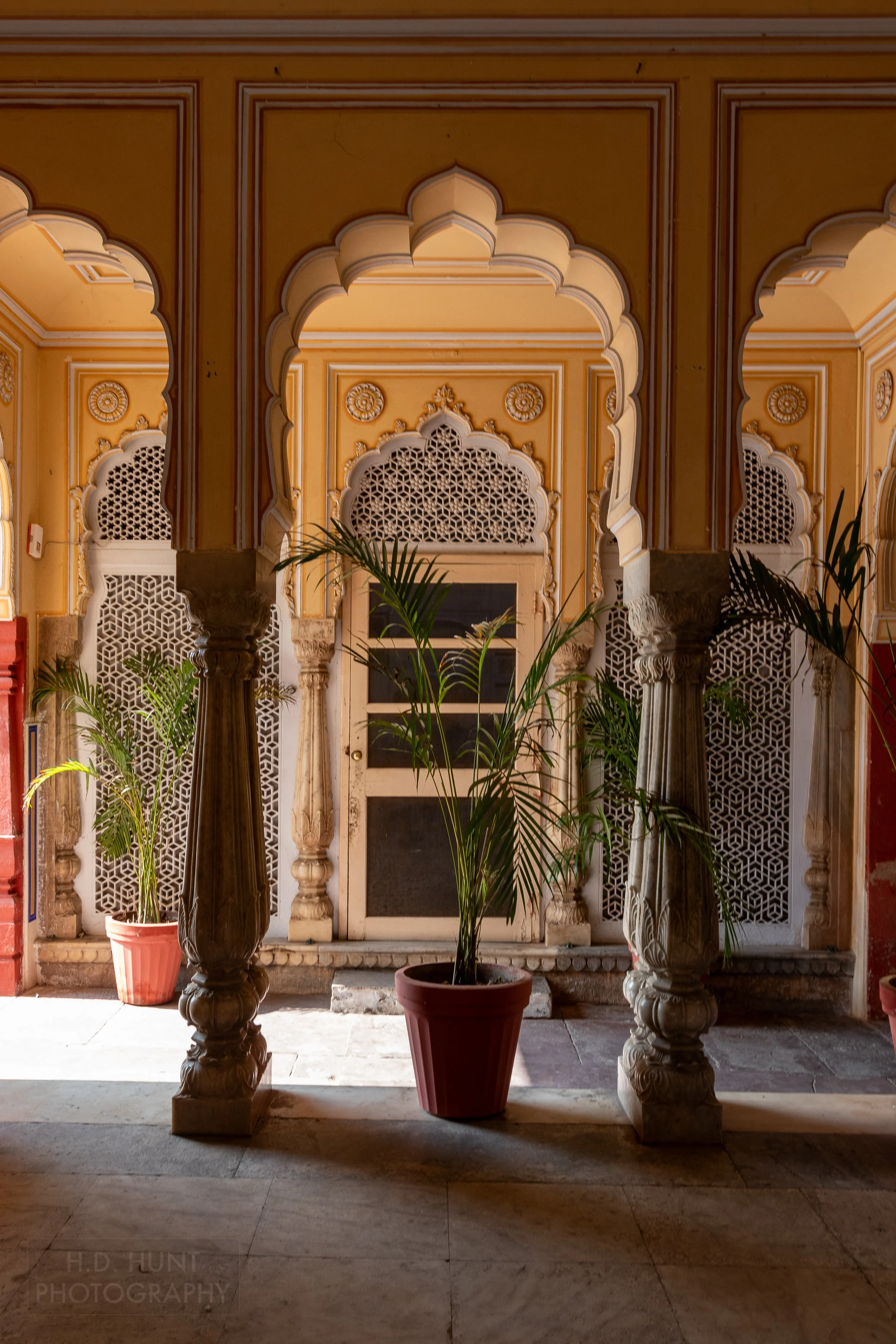 A potted plant sits in a colonnade within City Palace, Jaipur, India.
