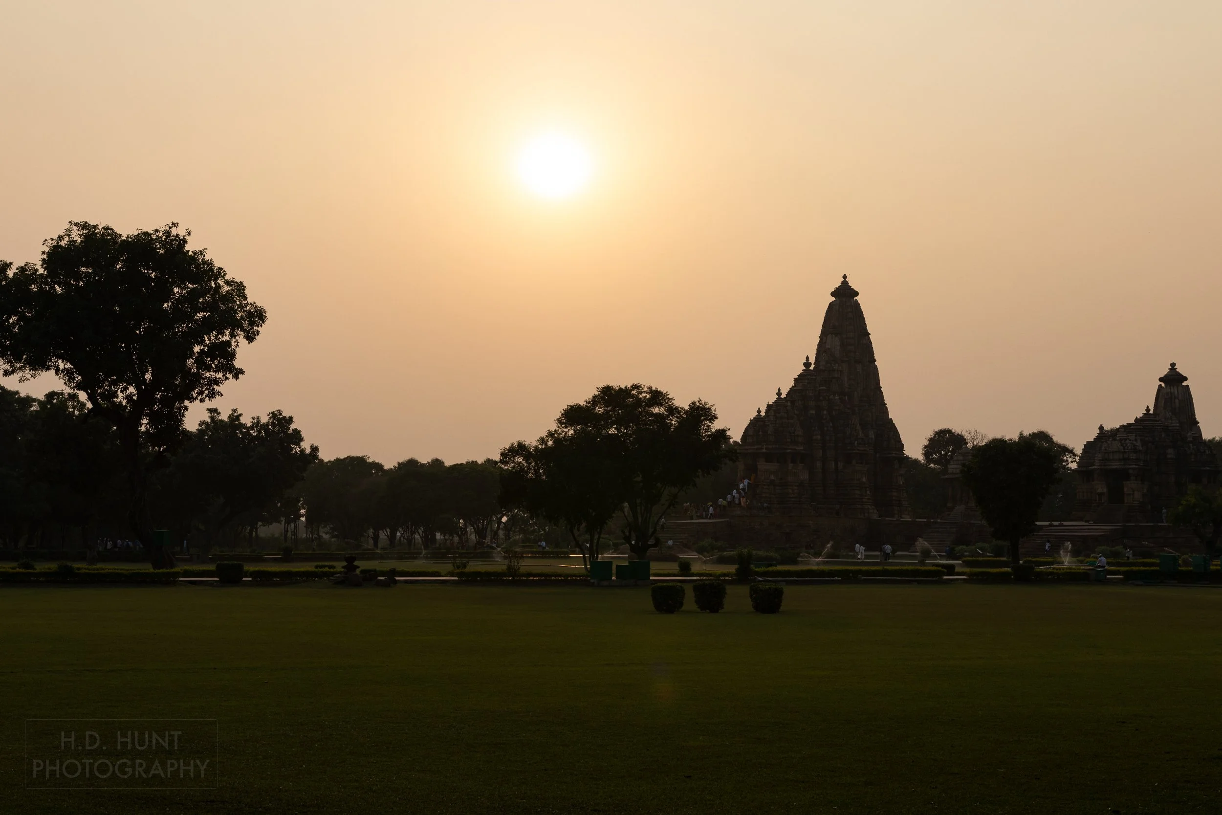 The orange sun begins to set over the Khajuraho Group of Monuments, India.
