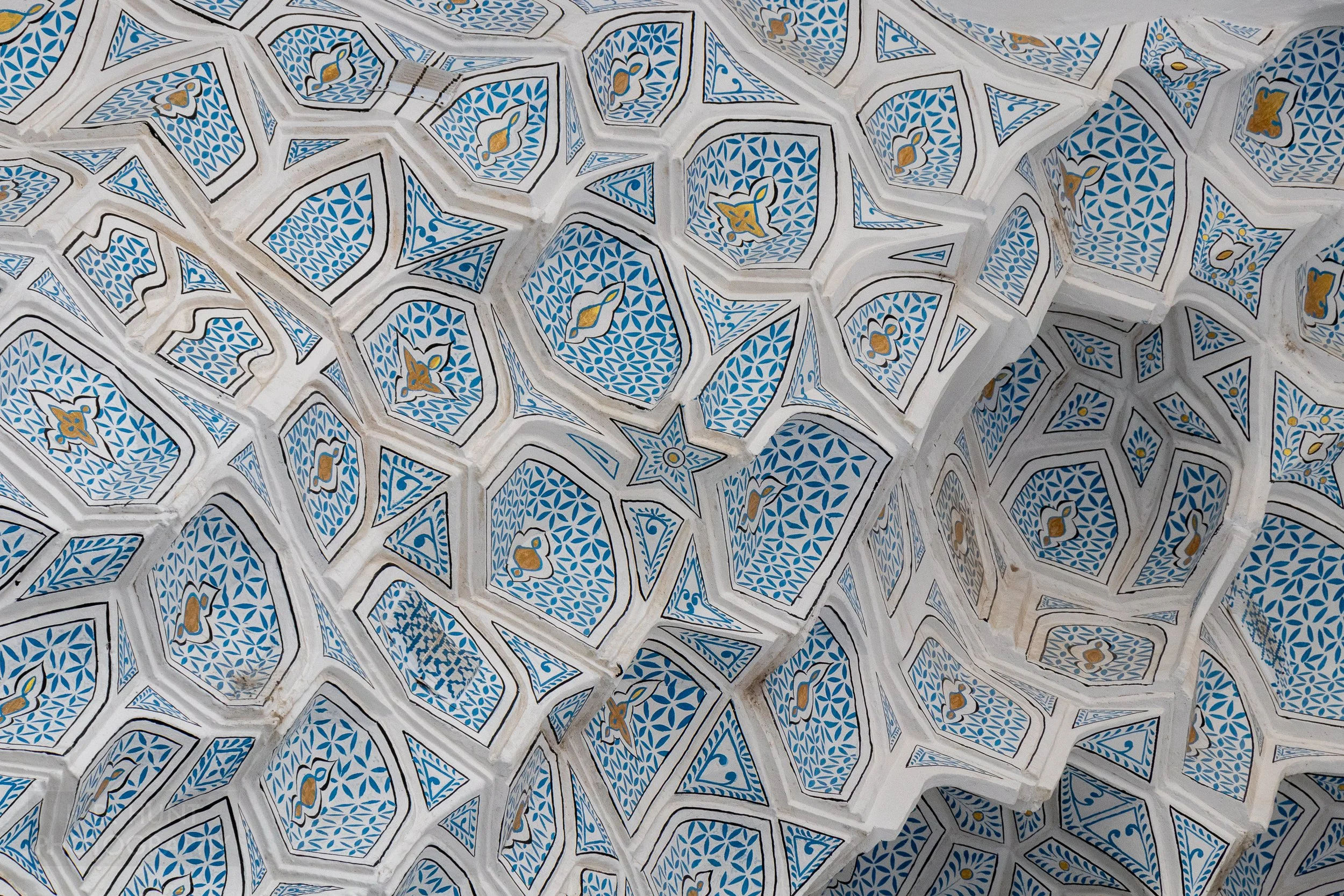 Close-up of a blue and white muqarnas honeycomb ceiling pattern at the Guri Amir mausoleum in Samarkand, Uzbekistan.