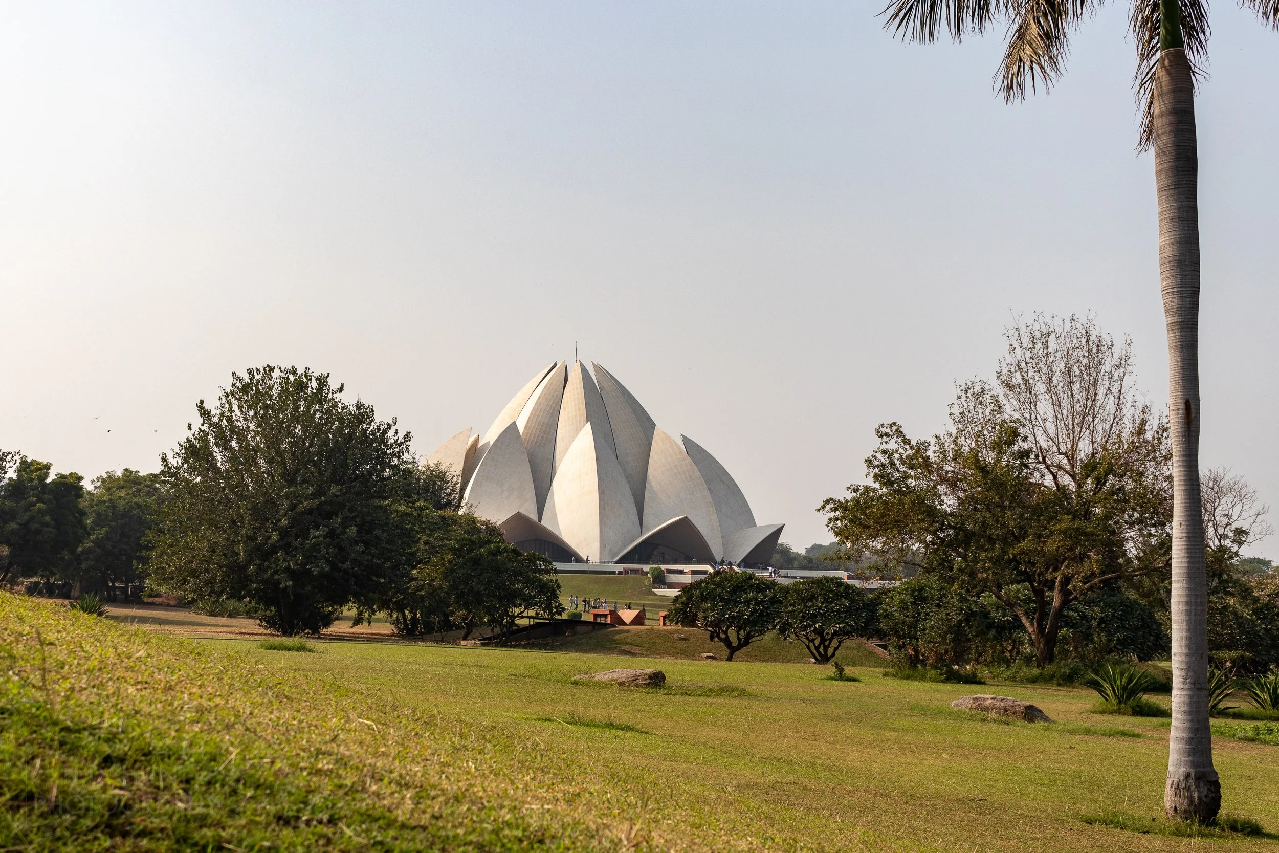 The white stone Lotus Temple is seen behind manicured gardens, Delhi, India.