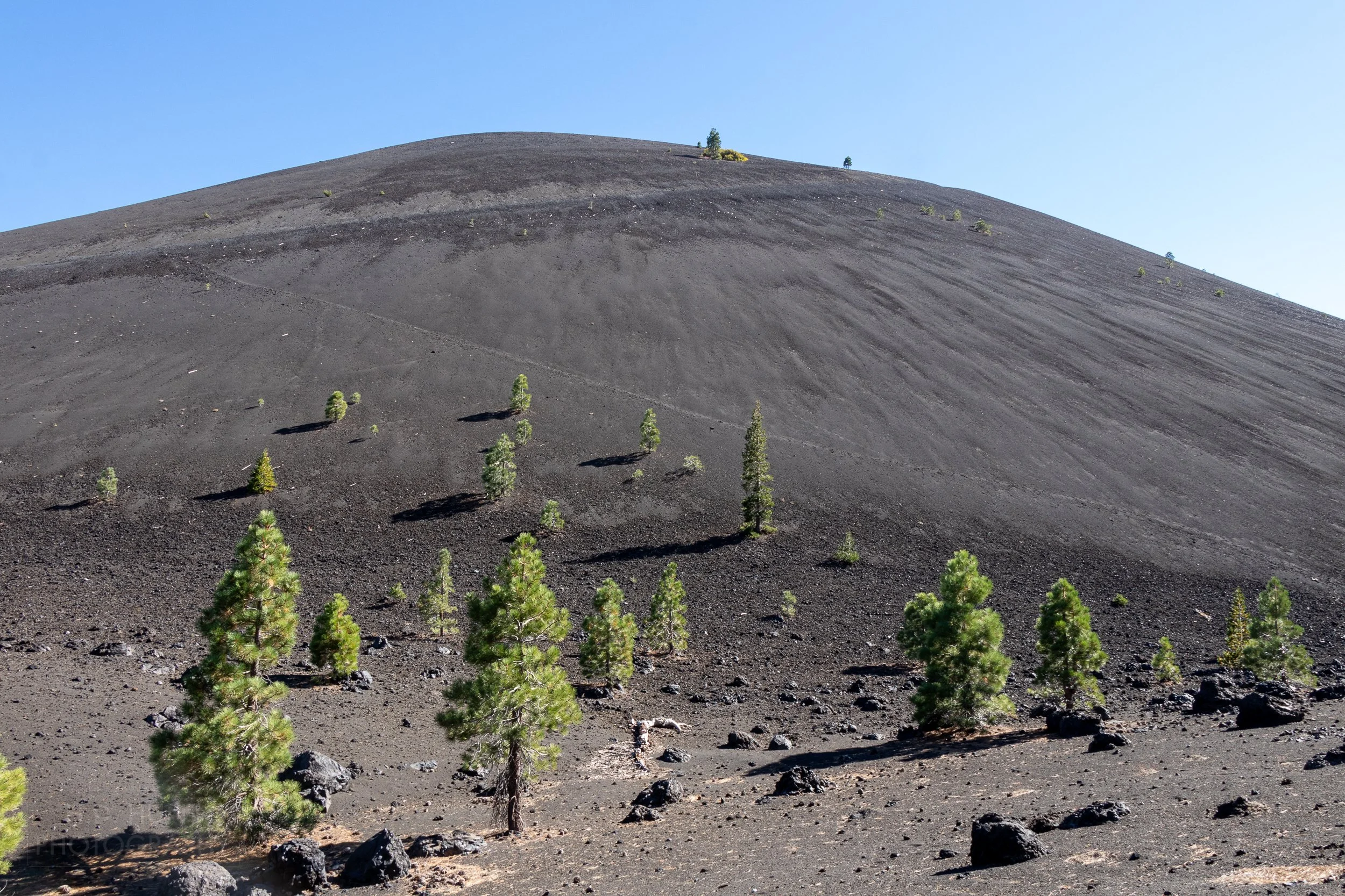 The large black basalt mound that is known as Cinder Cone volcano rises above Lassen Volcanic National Park, California, United States.