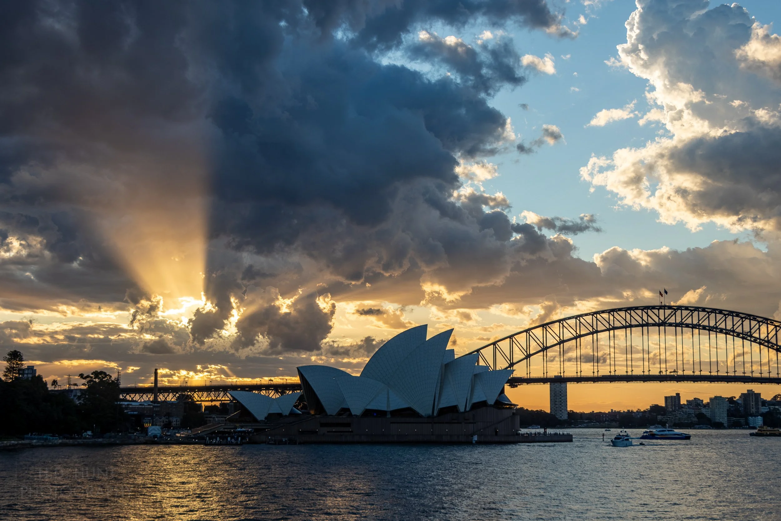 Sunlight peeks through clouds behind the Sydney Opera House, Sydney, Australia.