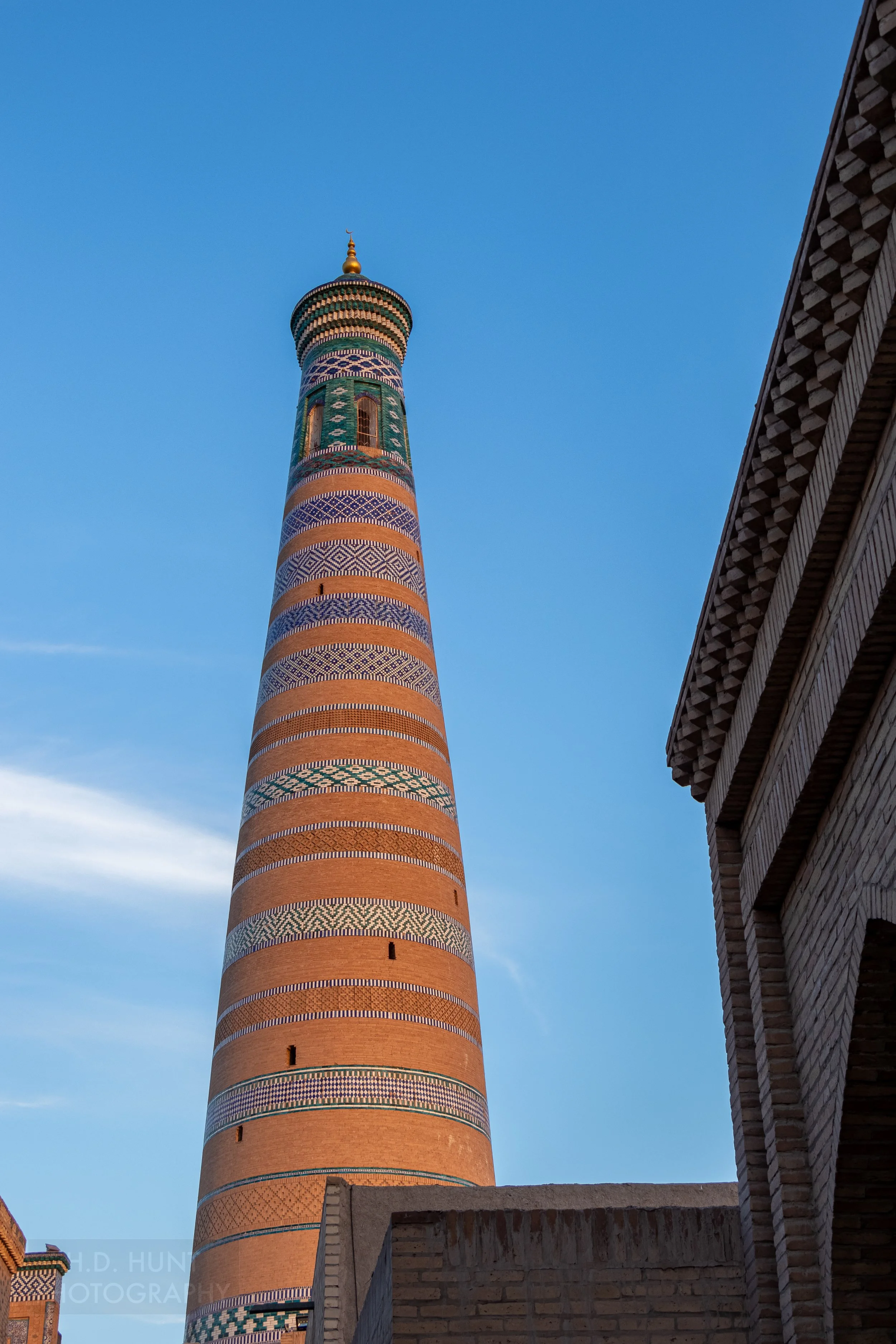 The Islam Khoja Minaret rises against a blue sky in Khiva, Uzbekistan.