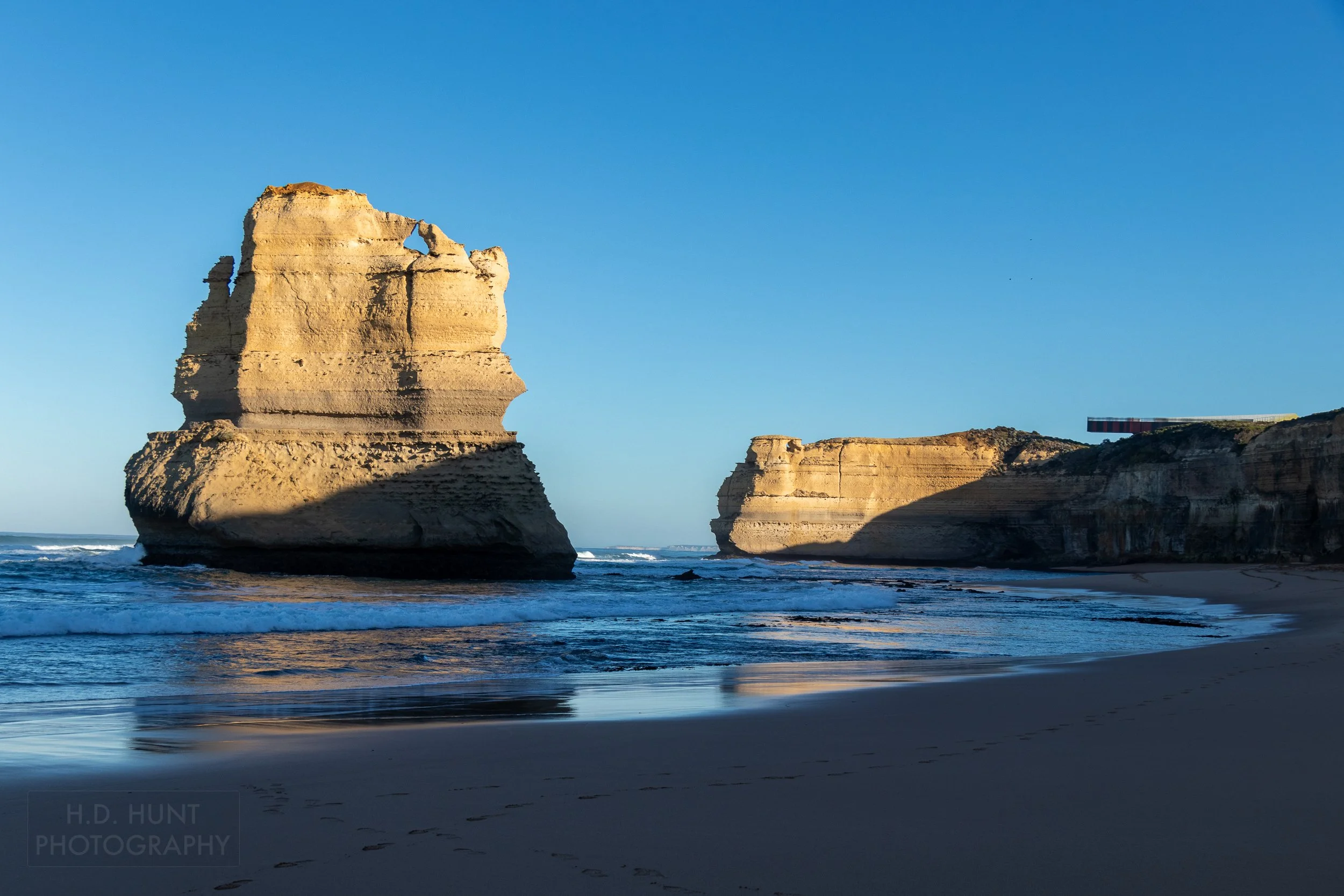 A tall rock cliff is seen above the calm waters next to Gibson Beach, Victoria, Australia.