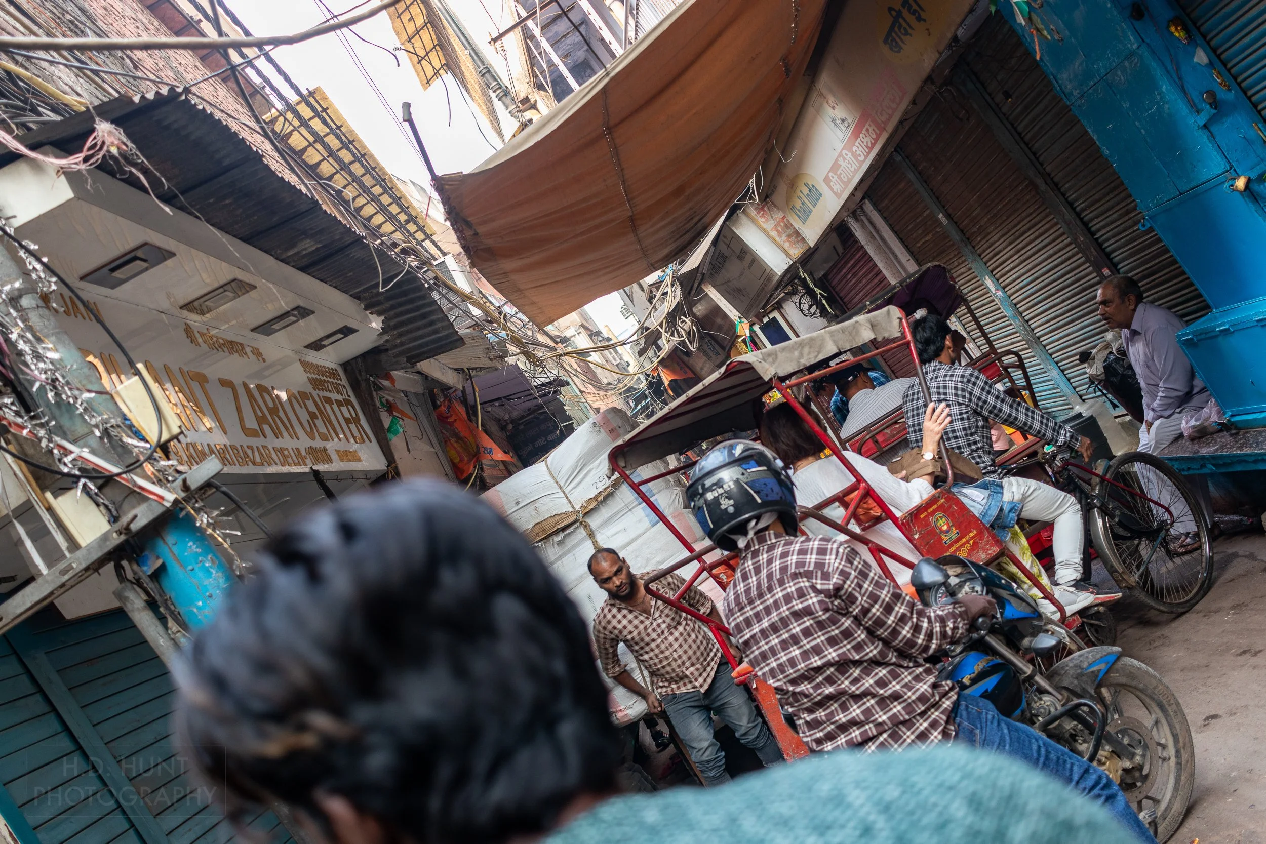 A man pulls a large wheelbarrow through a narrow alleyway, Chandni Chowk, Delhi, india