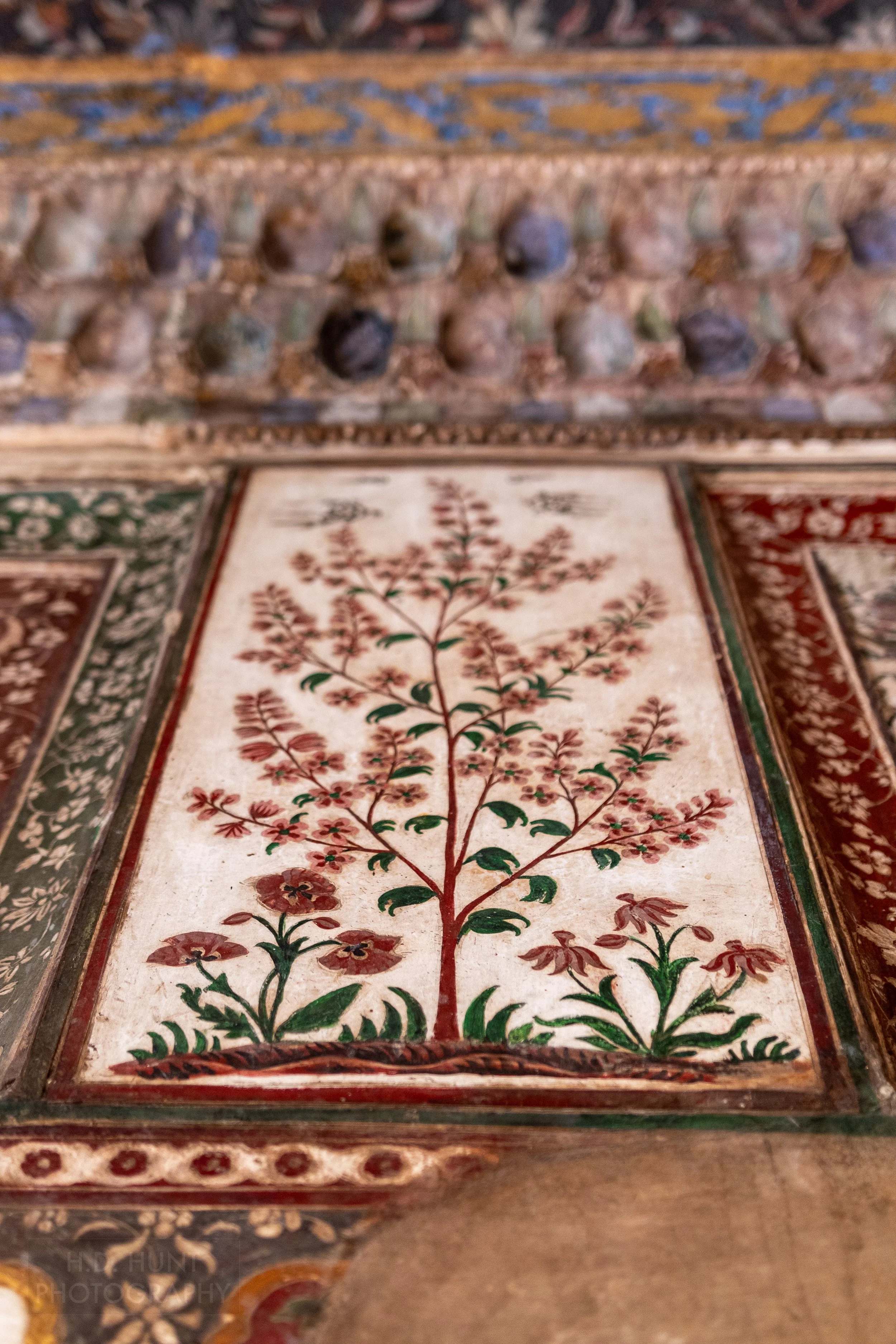 A painted tile of a red tree with green and pink flowers is seen on the wall of the Tomb of I’timad-ud-Daulah, Agra, India.