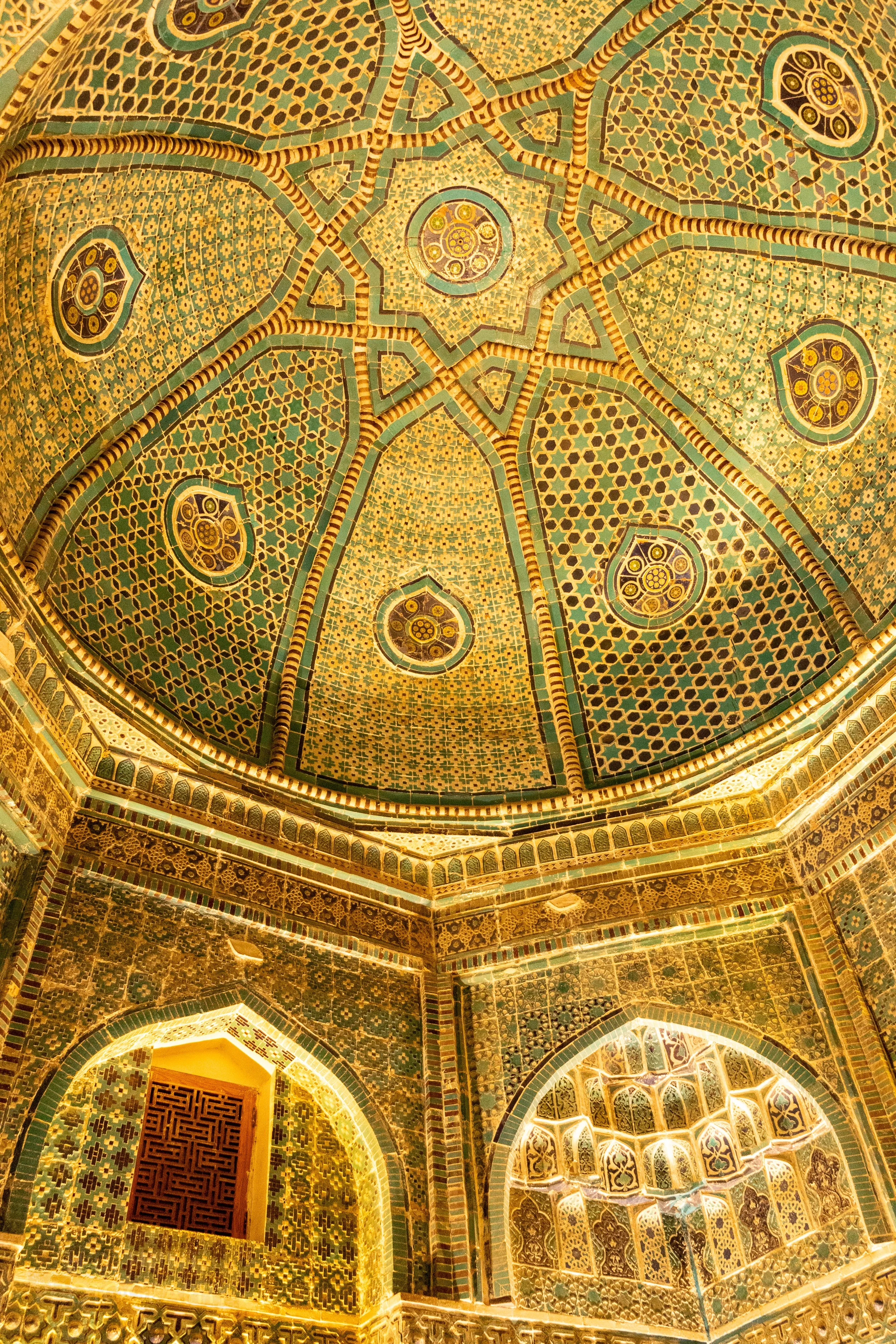 Green and yellow tiled dome interior of a mausoleum at the Shah-i-Zinda necropolis in Samarkand, Uzbekistan.