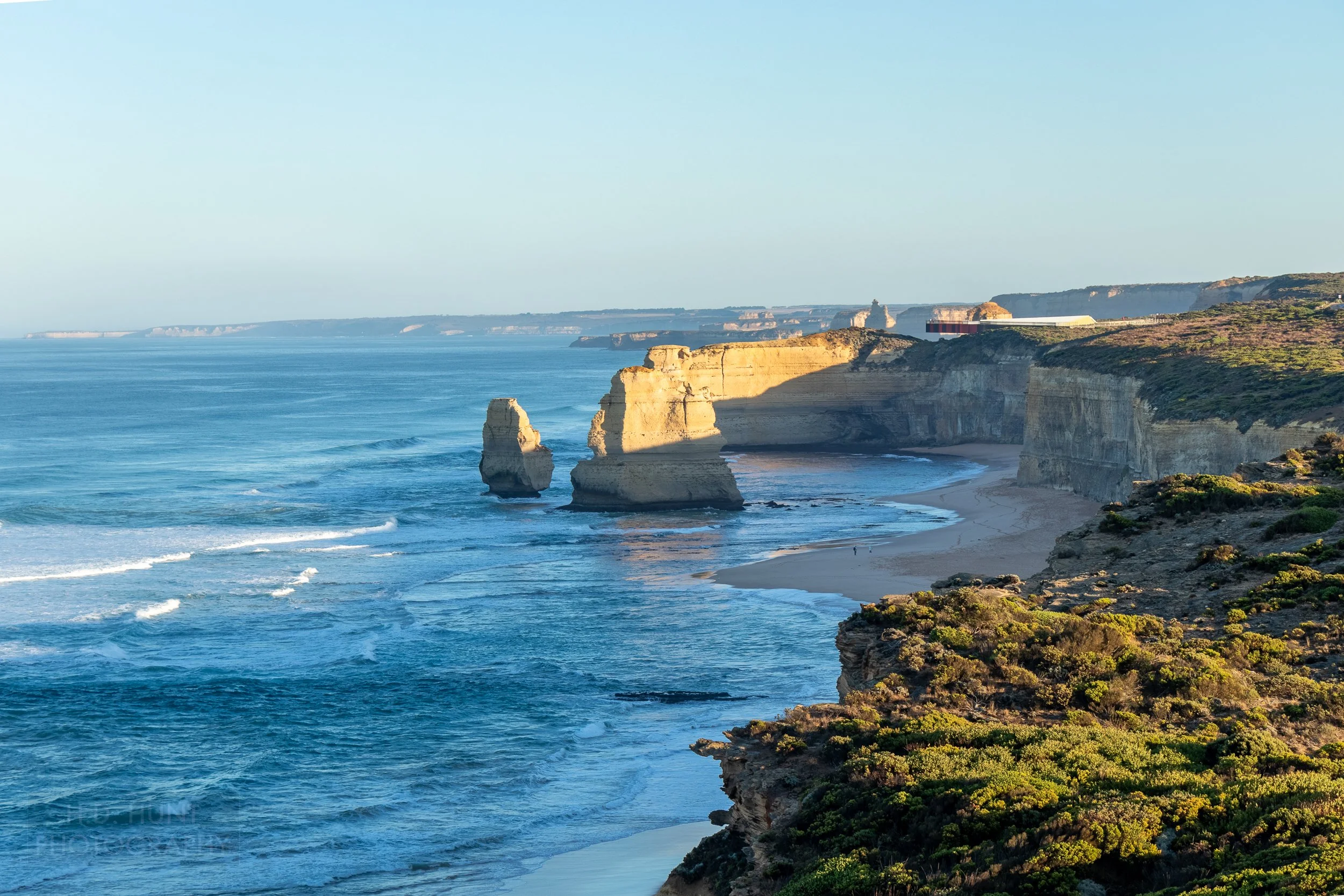 Two cliffs rise from the blue waters of the Southern Ocean along the beach beneath the Gibson Steps, as seen from The Great Ocean Walk, Victoria, Australia.