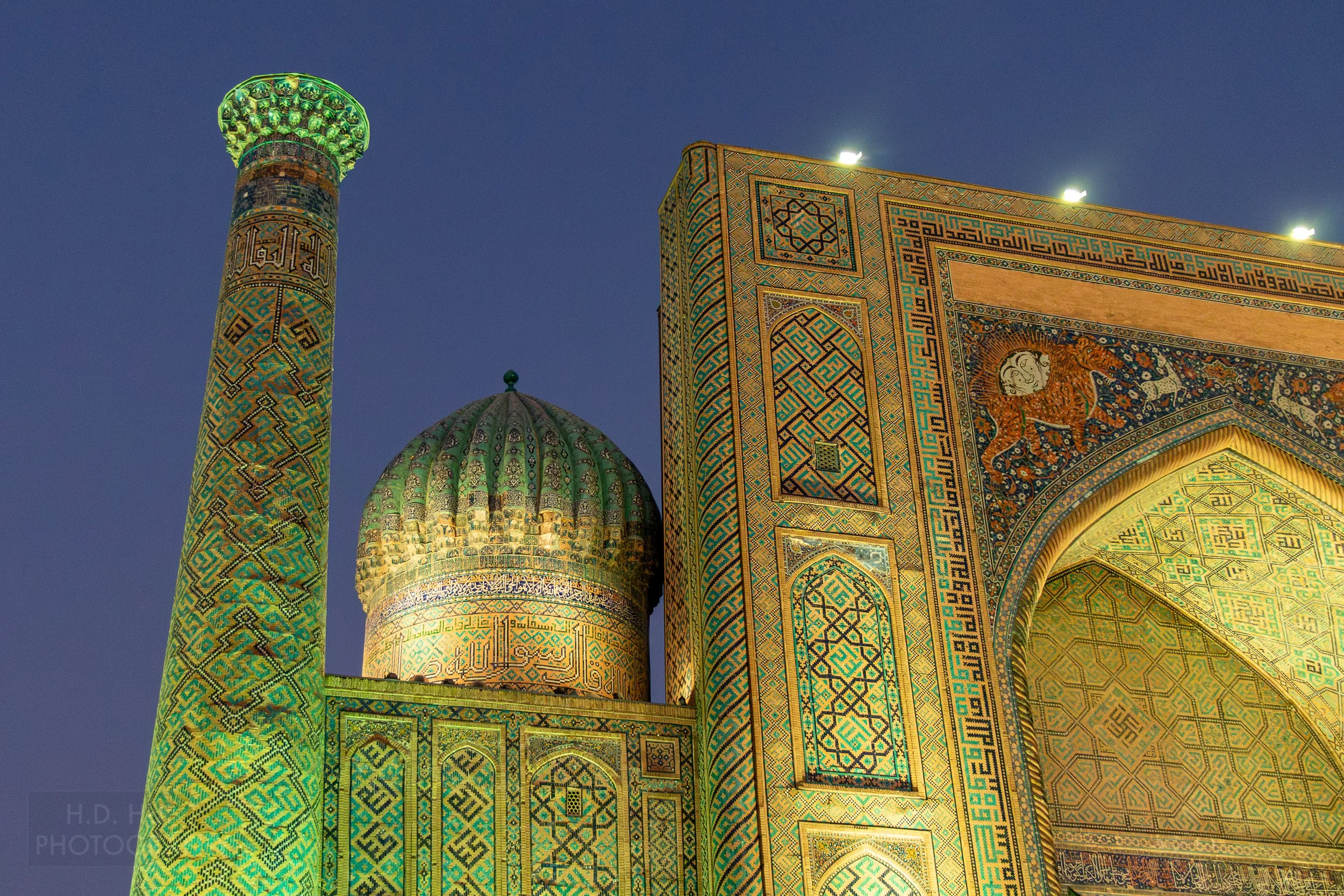Exterior of the Sher-Dor Madrasa illuminated with green light at the Registan in Samarkand, Uzbekistan.