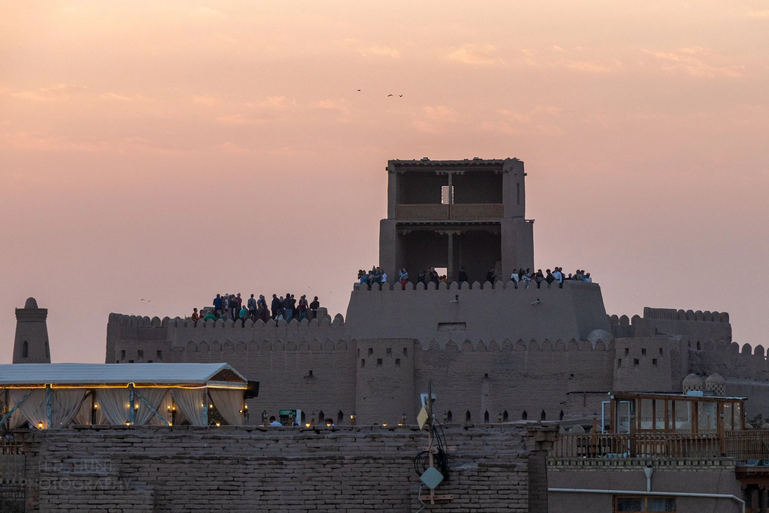 Visitors stand atop the Kuhna Ark to view and photograph the sunset over Khiva, Uzbekistan.