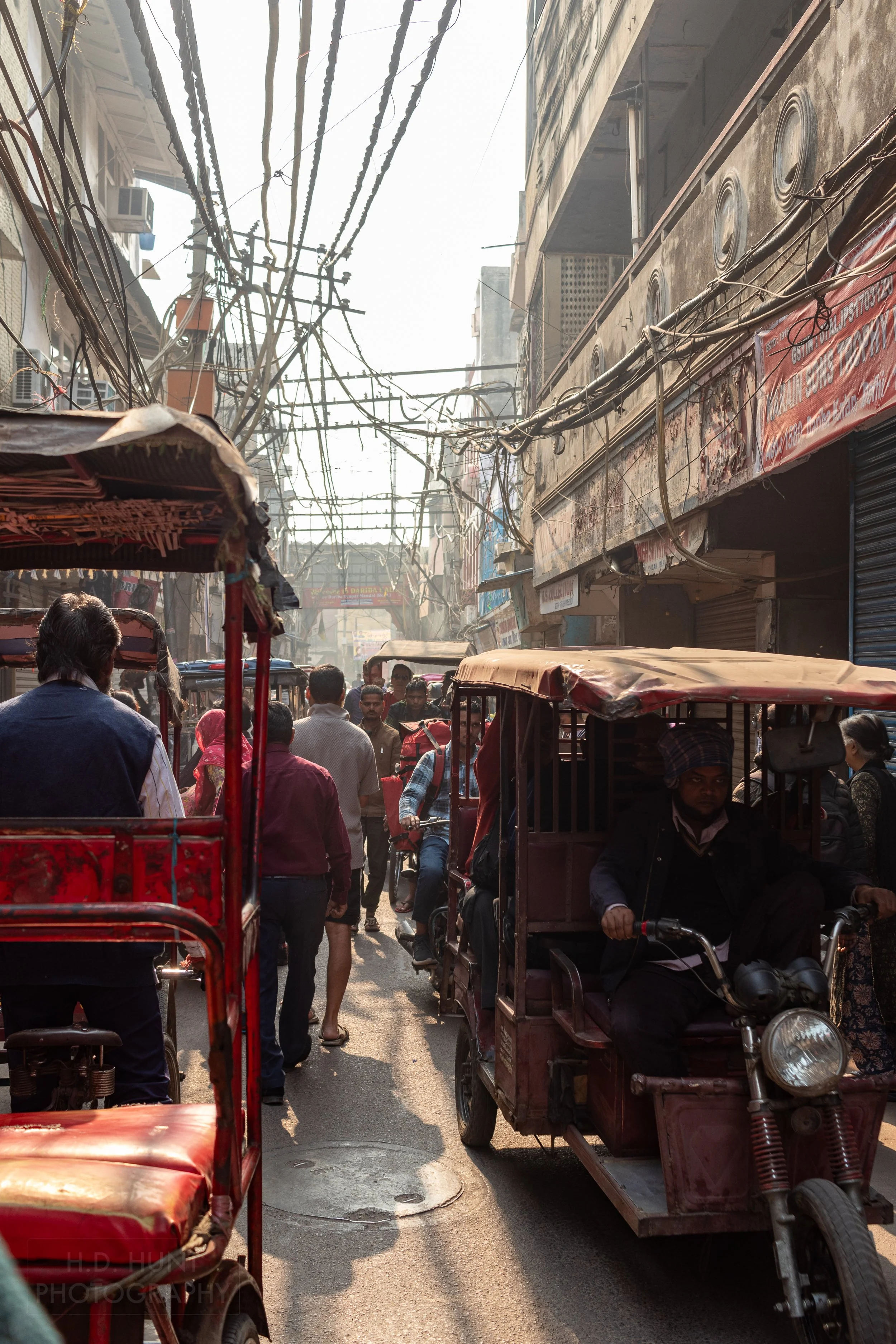 Several pedestrians and carts traverse a narrow alleyway, Chandni Chowk, Delhi, India.