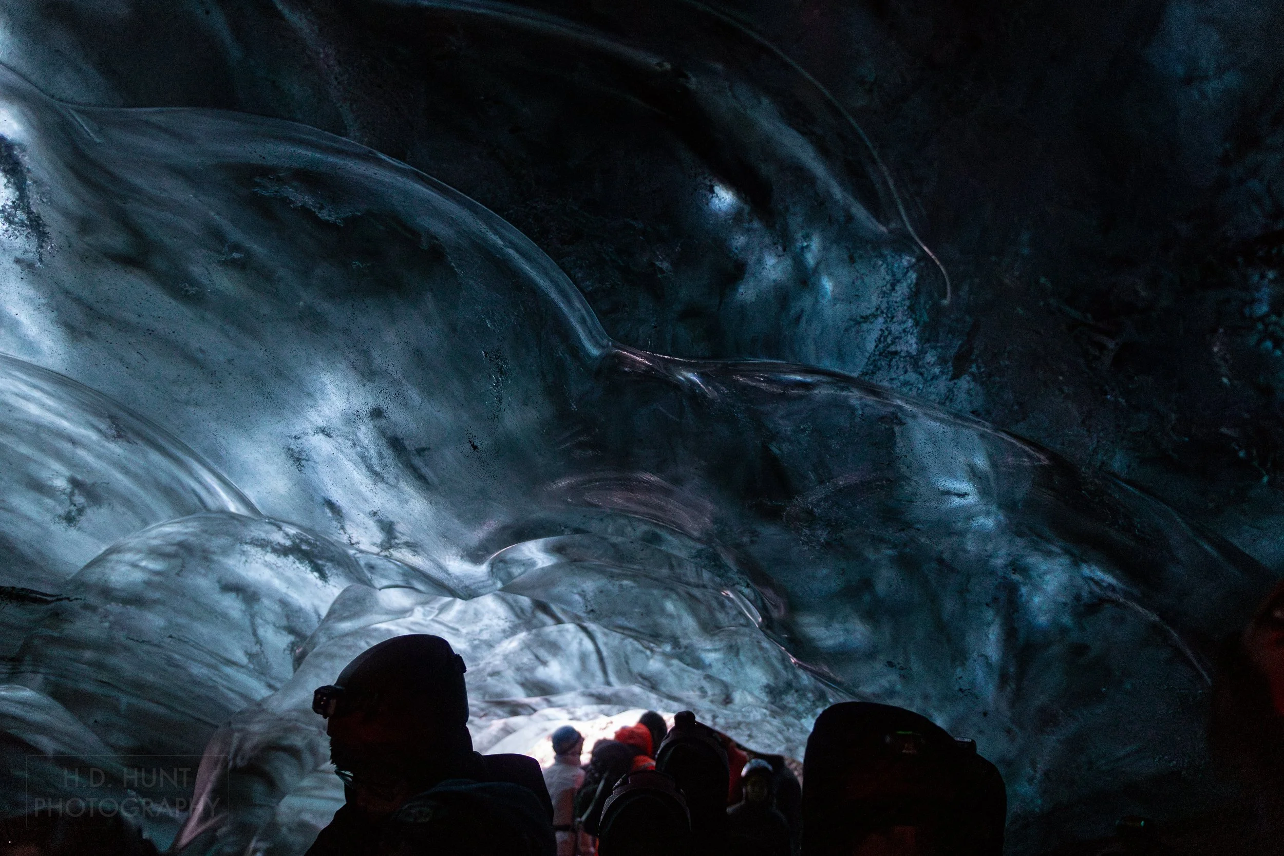 Silhouetted visitors and the wall of an ice cave is seen at Vatnajökull, Iceland.