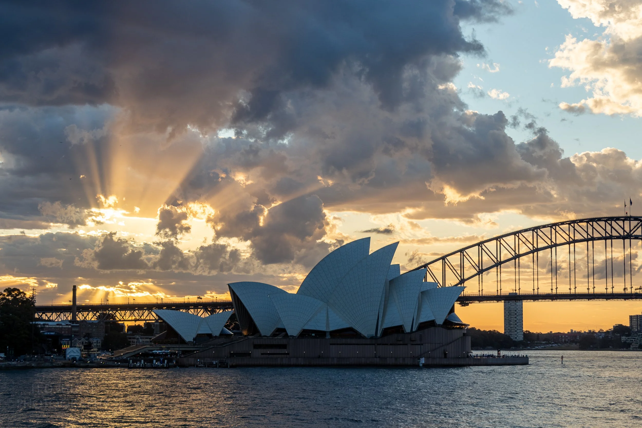 Sunlight peeks through clouds behind the Sydney Opera House, Sydney, Australia.