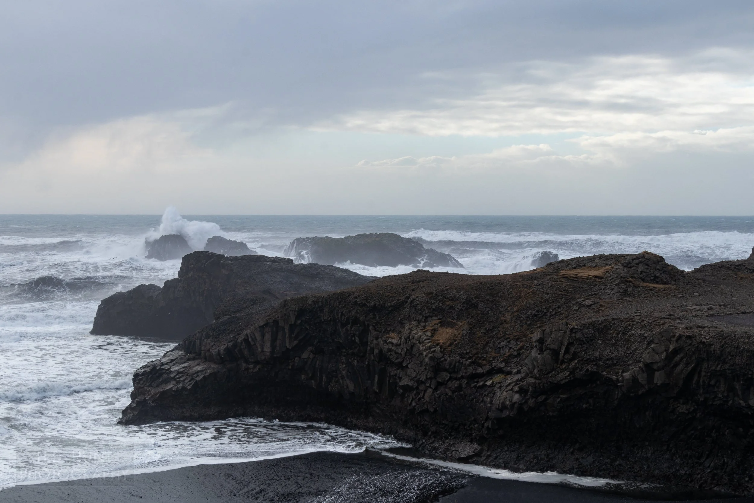 Waves crash into a point-of-rocks at Dyrhólaey, Iceland.
