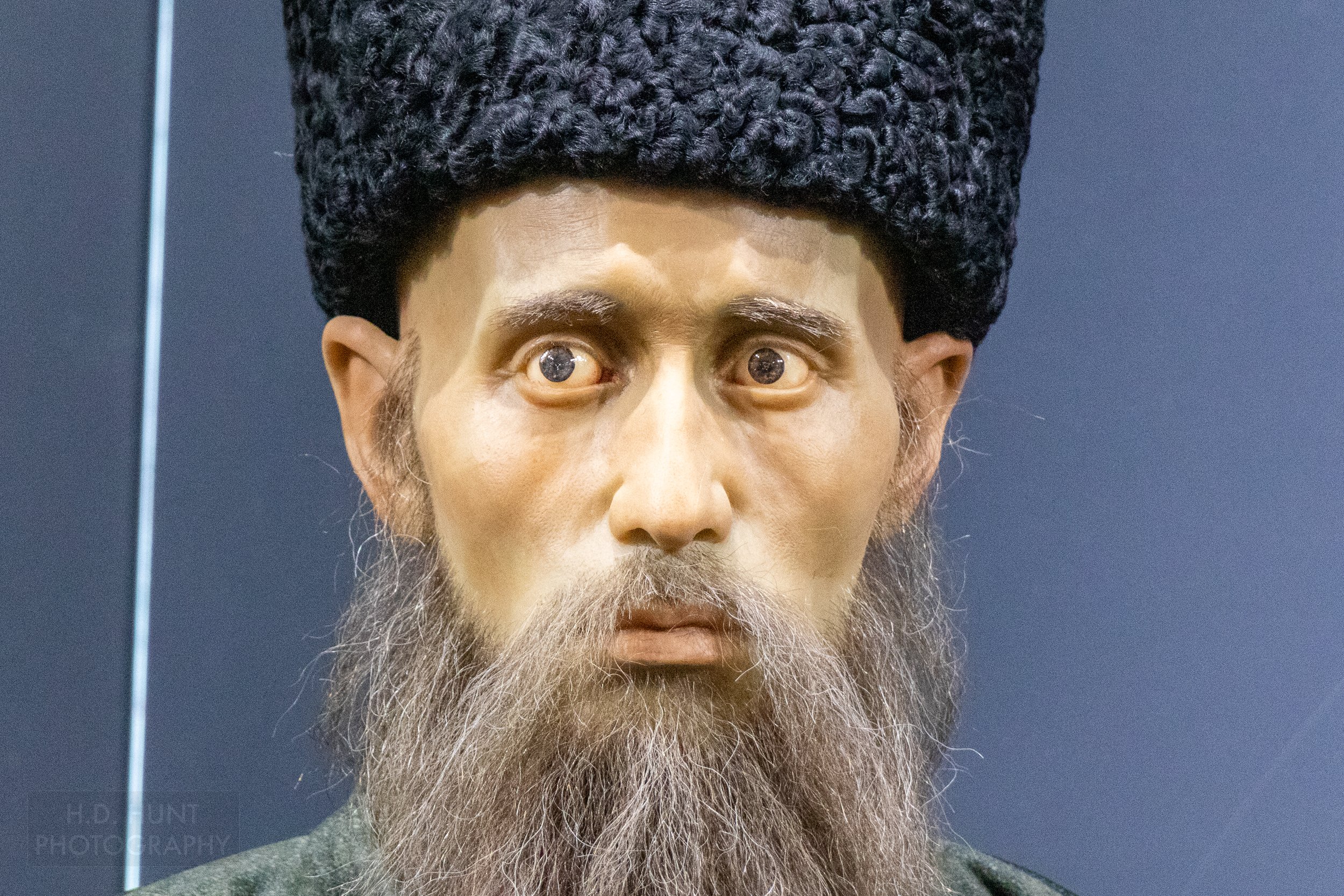 A life-sized figure of a man with a beard and a black woolen hat stands in the Museum of the Ruler and the Poet, Khiva, Uzbekistan.