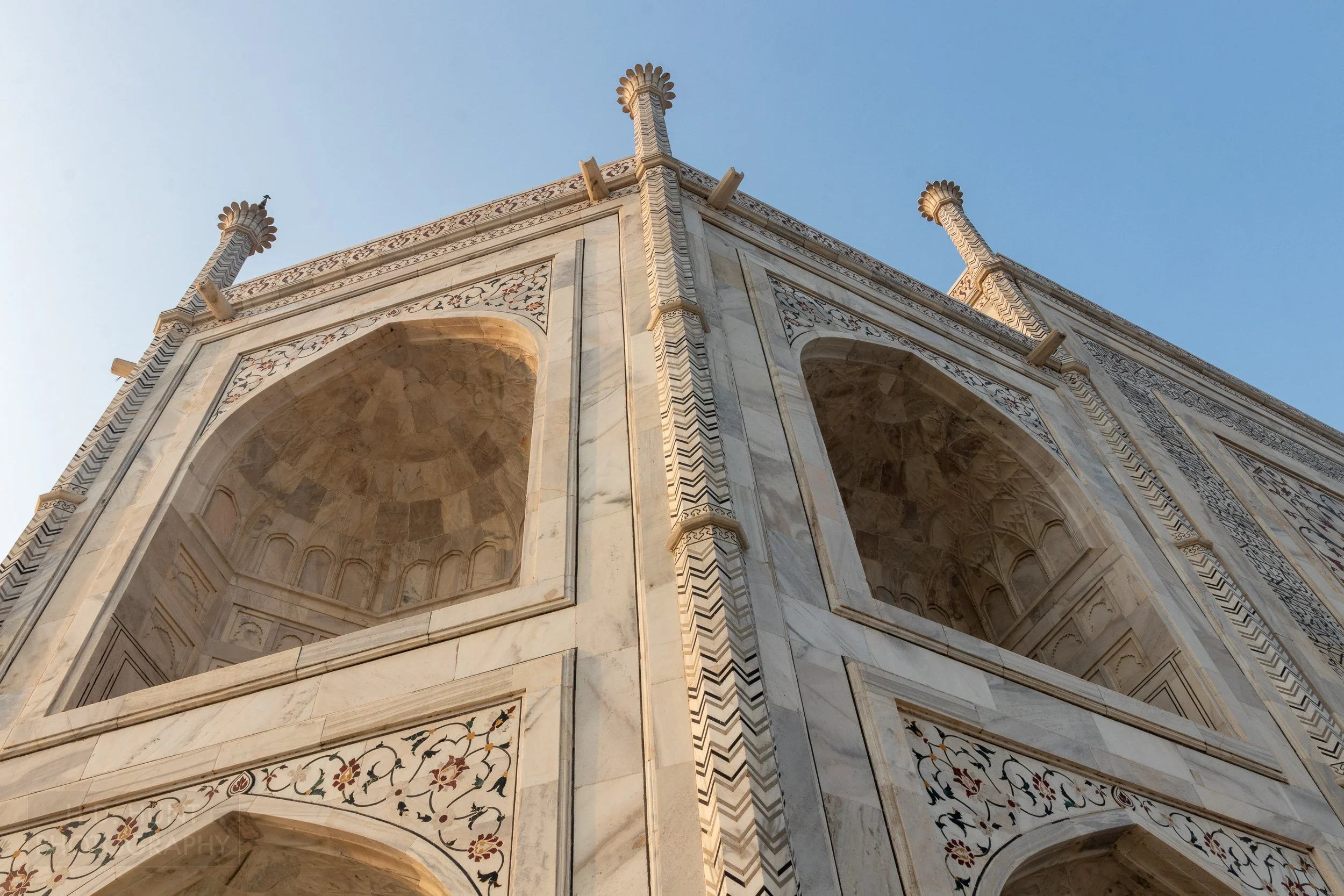 A close-up of white columns featuring a black and tan zig-zag pattern on the exterior of Taj Mahal, Agra, India.