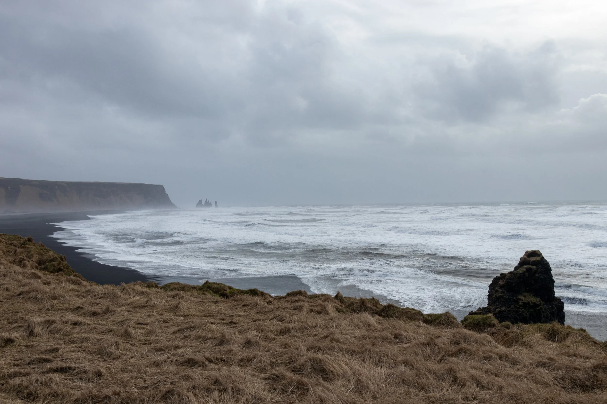 Waves crash into a black sand beach at Dyrhólaey, Iceland.