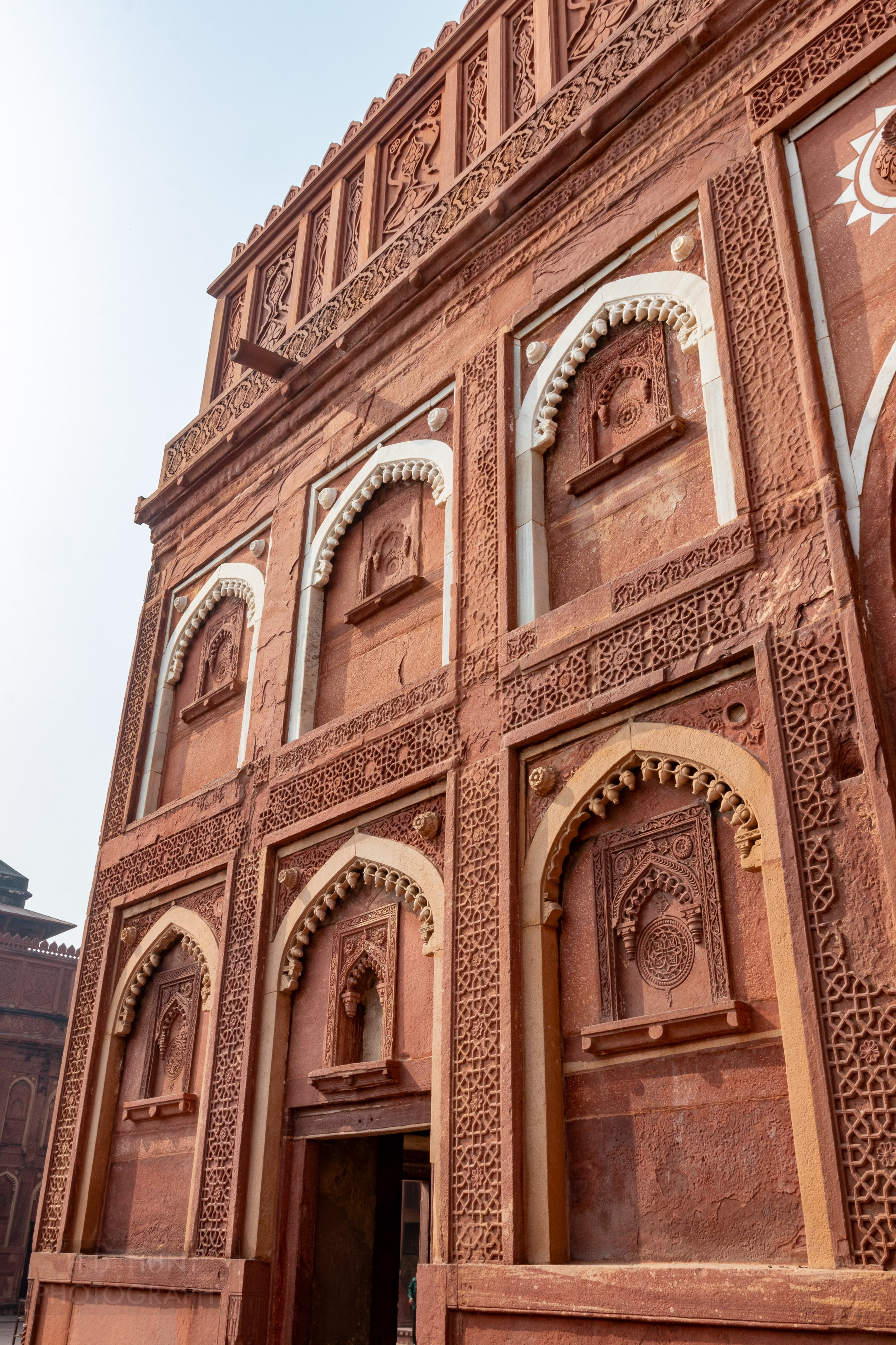 Several archways with white trim are seen on the red sandstone wall of a structure, Agra Fort, Agra, India.