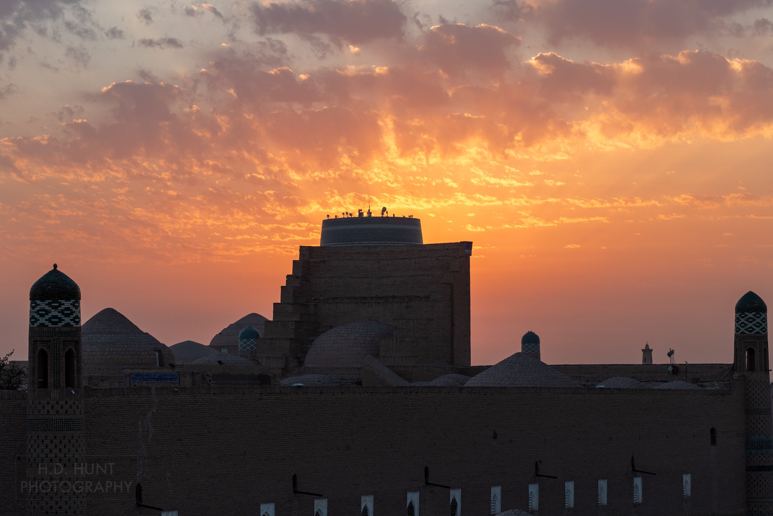The sun sets over Khiva resulting in bright orange, yellow, and pink colors filling the skies.