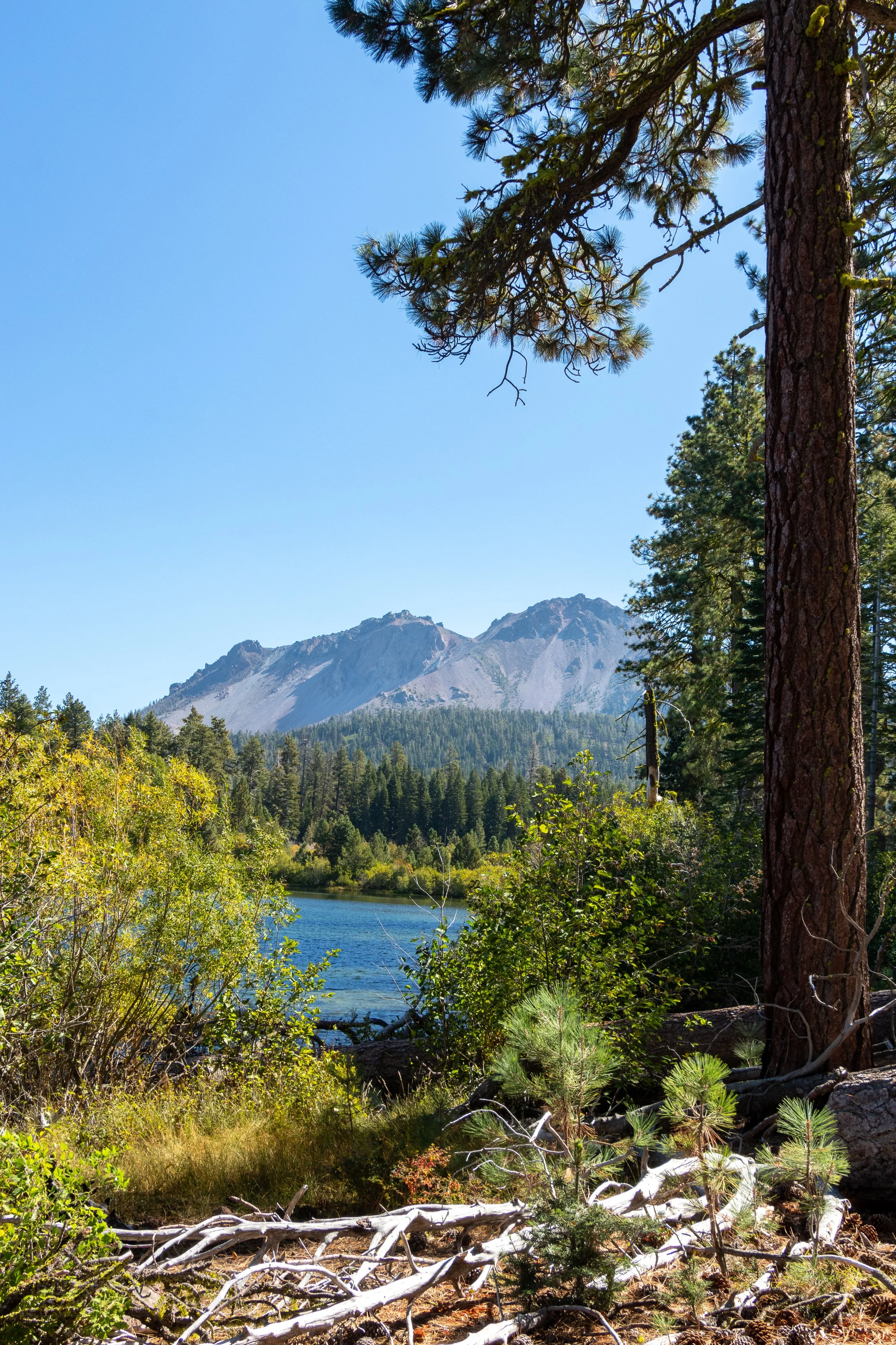Jagged mountains - known as Chaos Crags - appear behind a Manzanita Lake, Lassen Volcanic National Park, California, United States.